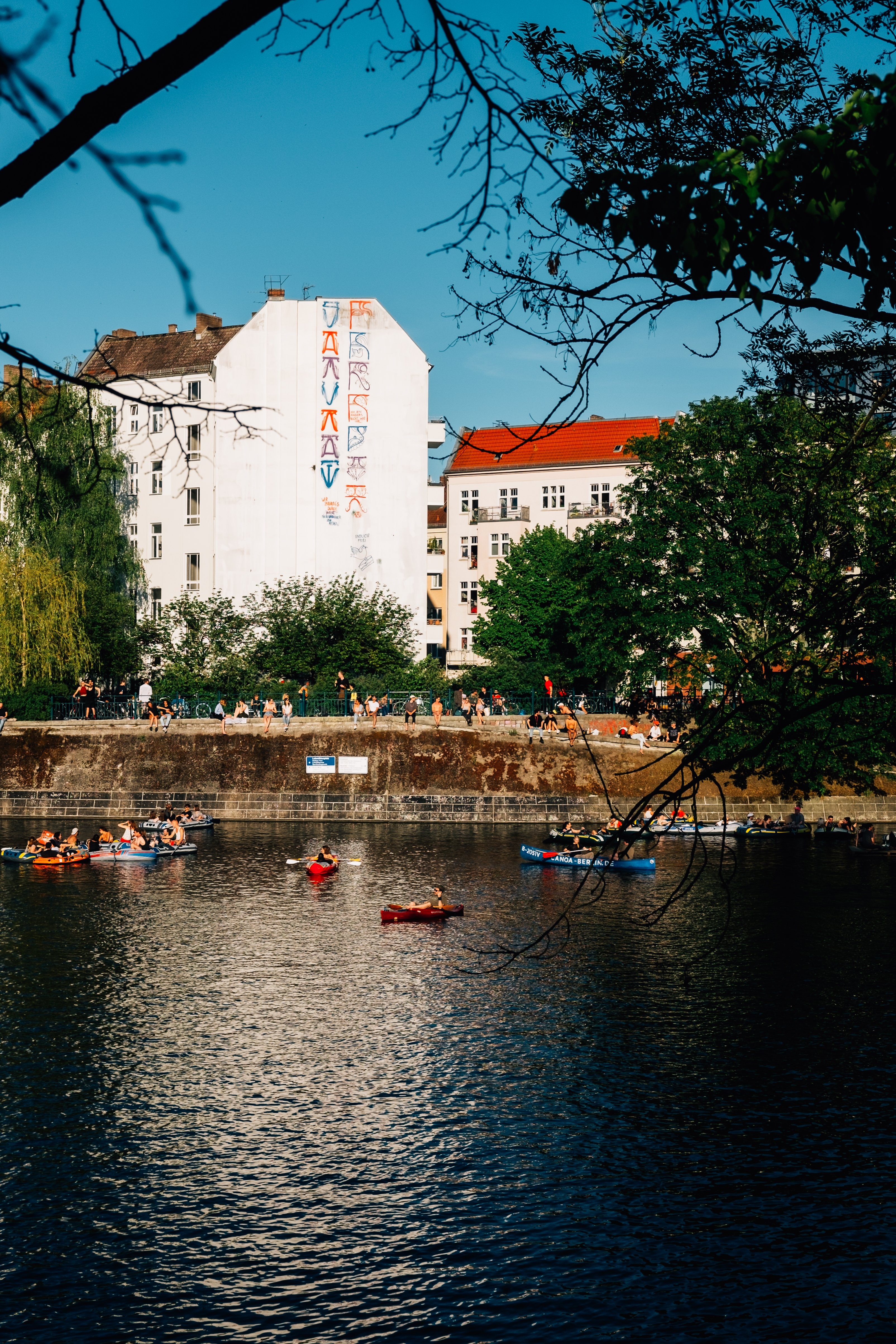 Des kayaks flottent dans la rivière avec des bâtiments derrière Photo 