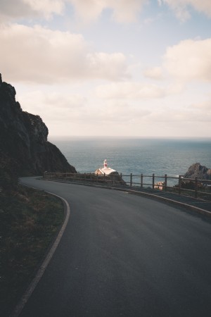 Route pavée sinueuse avec un phare au loin Photo 
