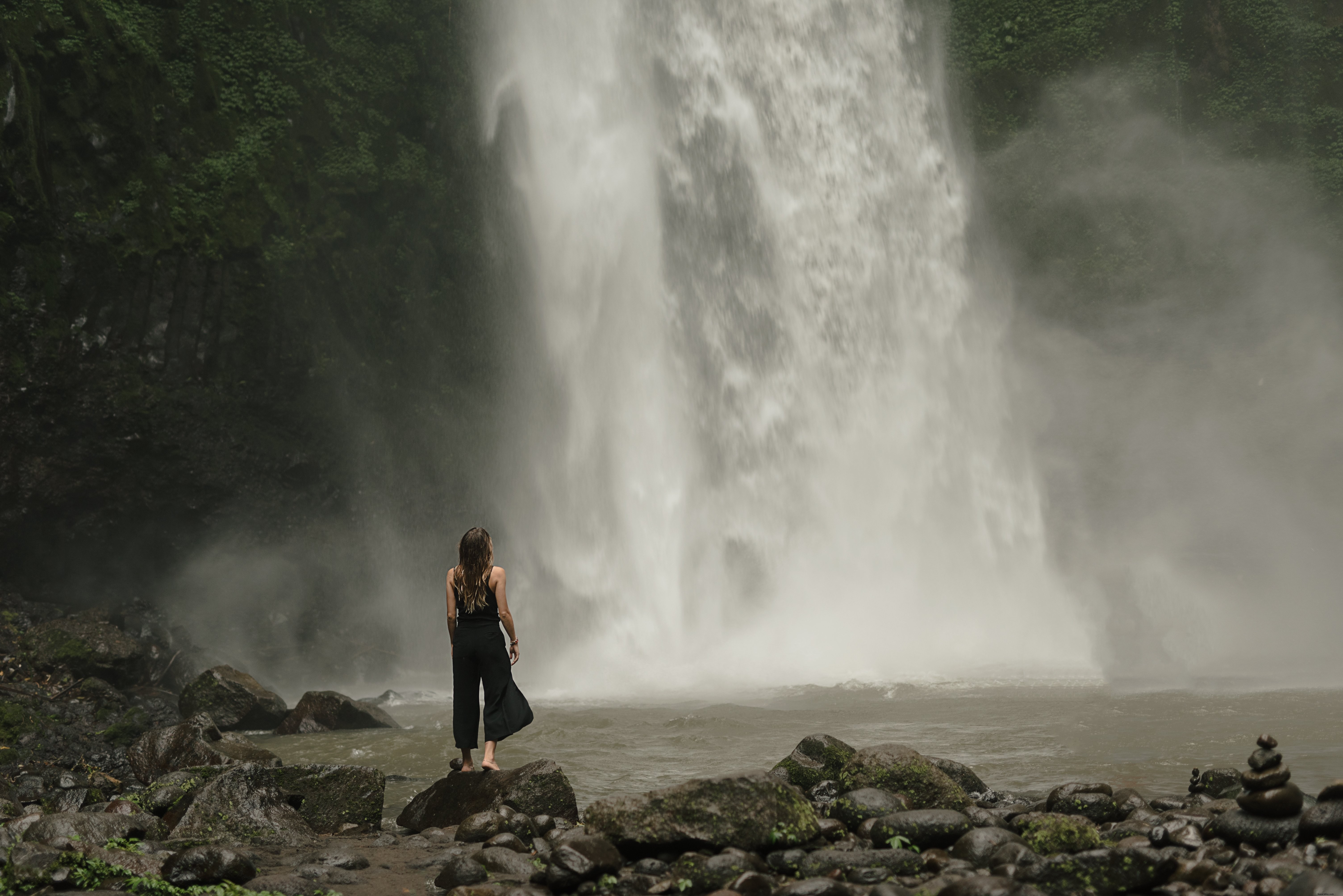 Foto de uma mulher para ao pé da cachoeira