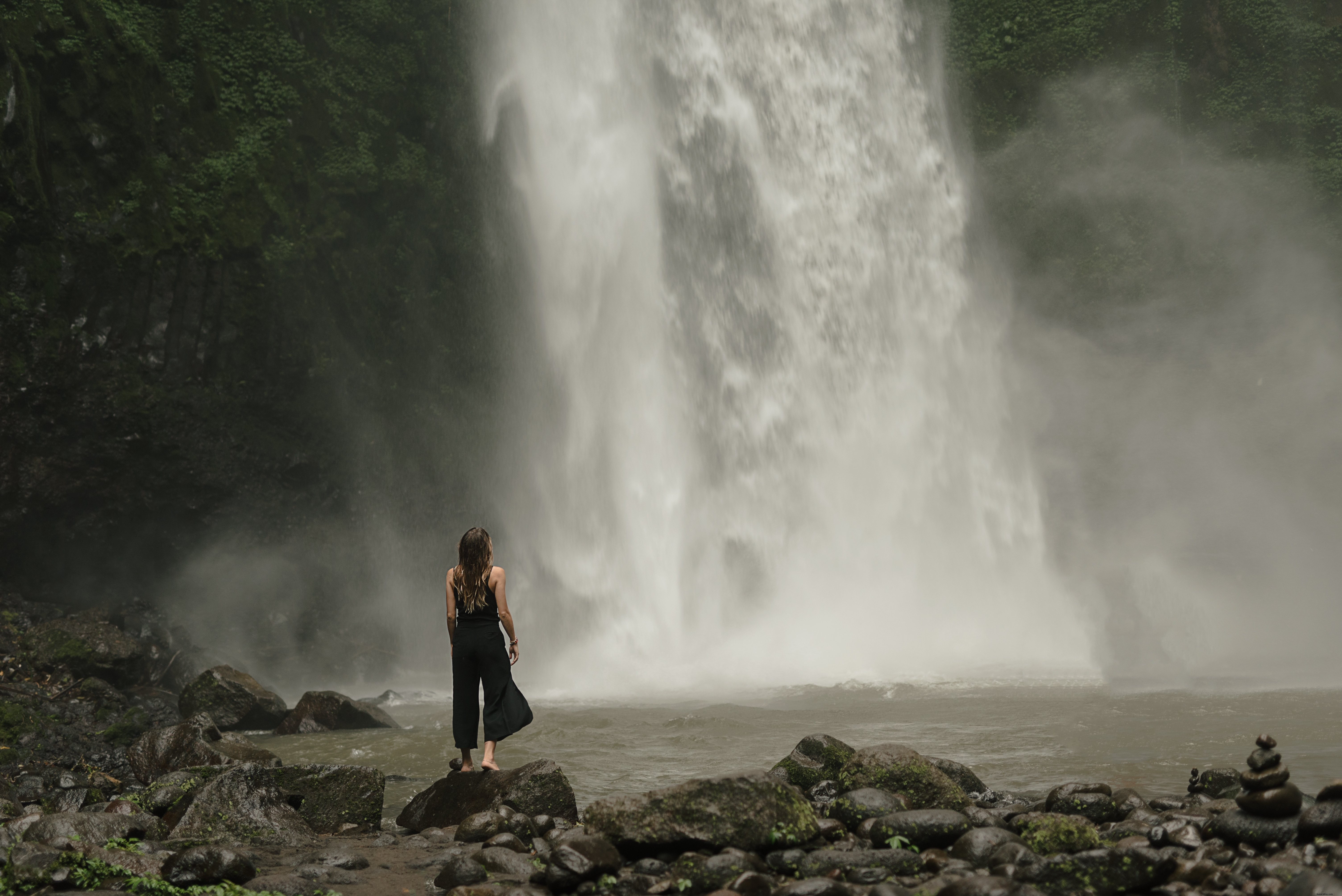 Femme s arrête au pied de la cascade Photo