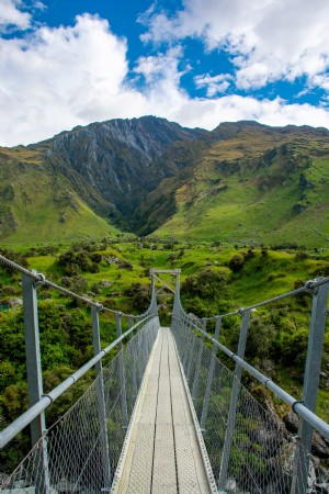 Ponte suspensa sobre campos e montanhas da Nova Zelândia