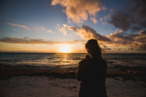 Mulher vendo foto na praia do nascer do sol