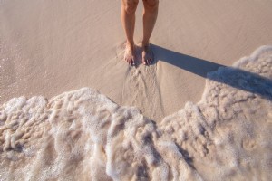 Foto de pies de mujer en la arena con olas