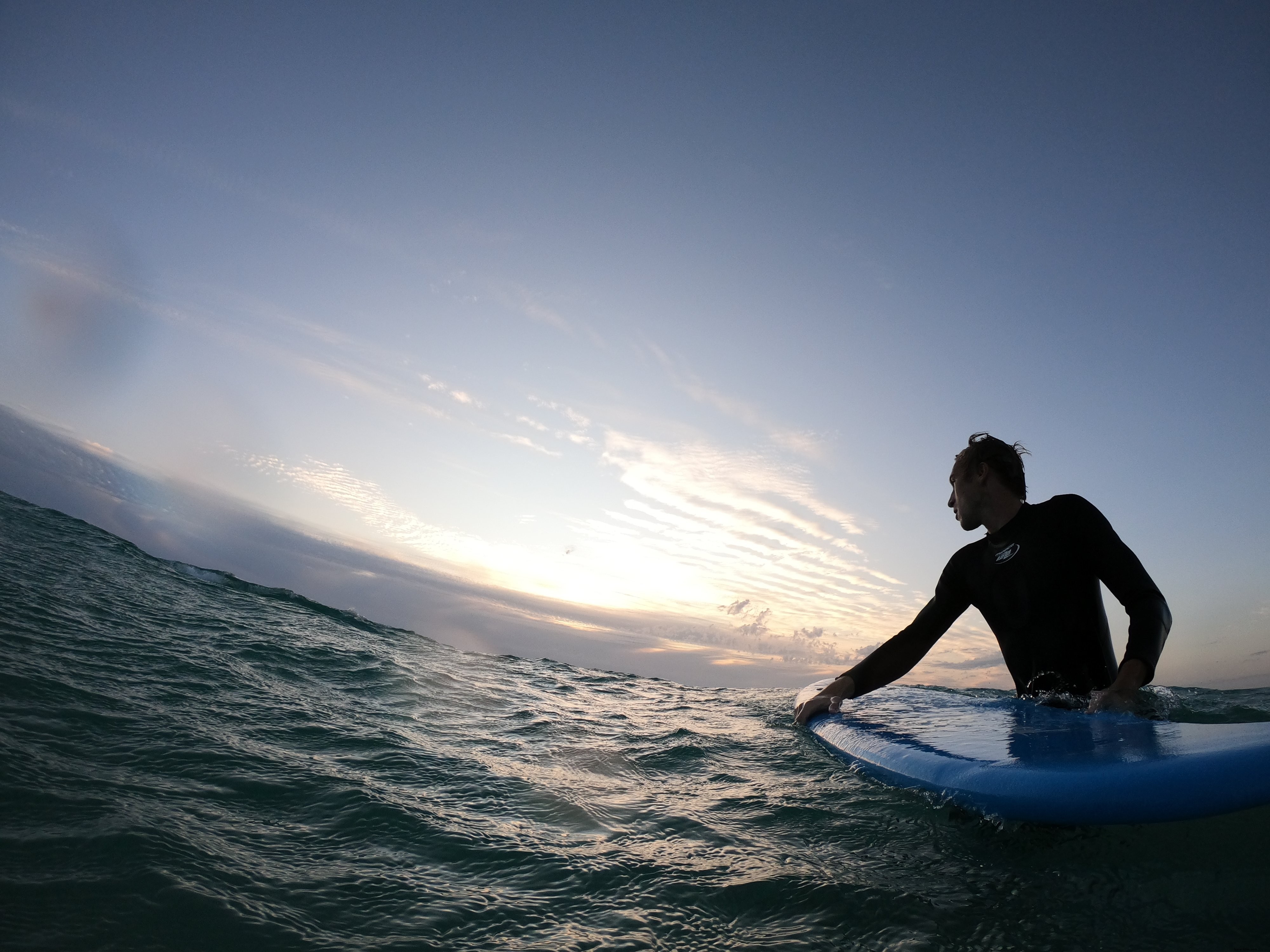 Persona in piedi nell acqua ondulata con in mano una tavola da surf
