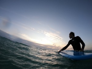 サーフボードの写真を持って波状の水に立っている人