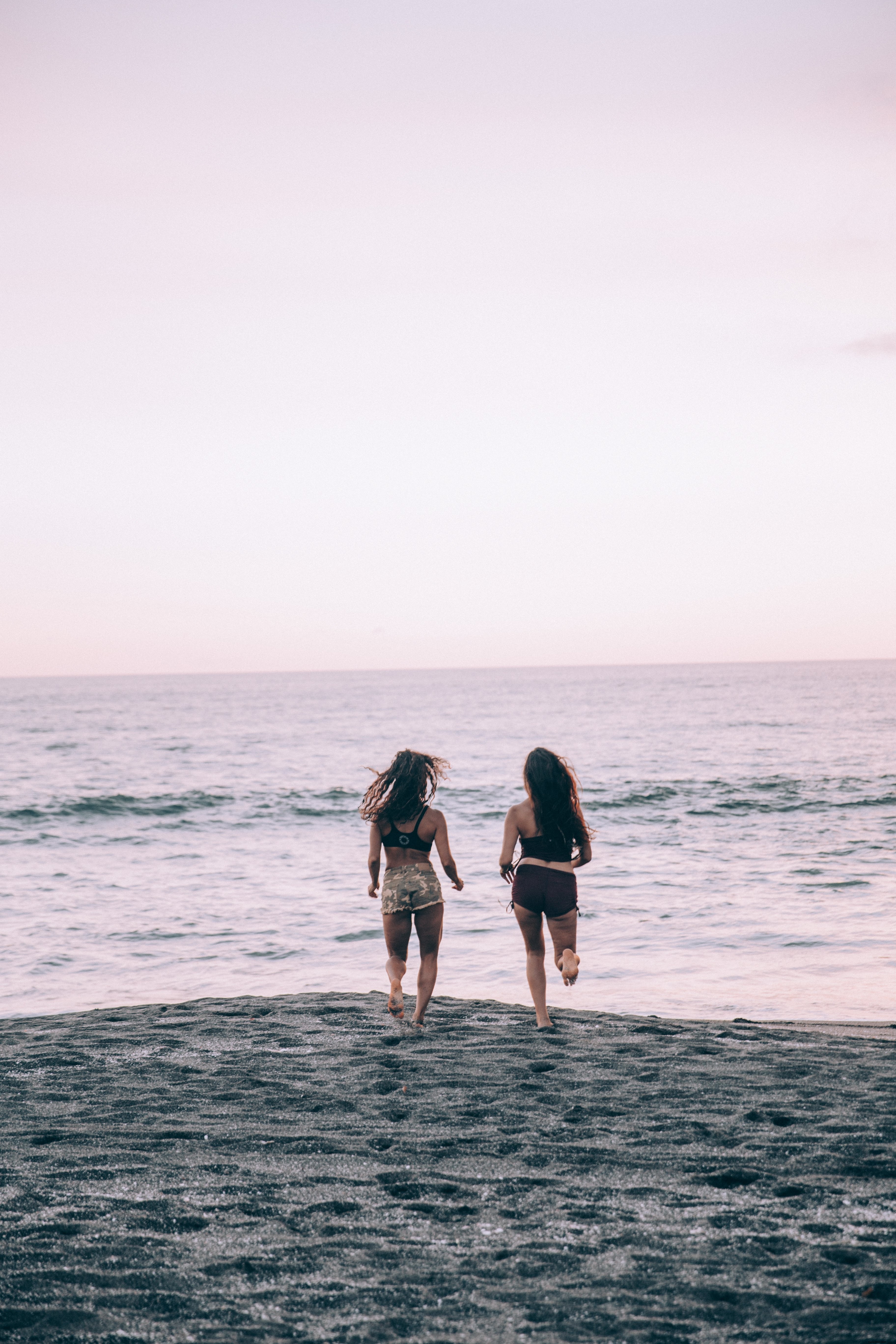 Due donne corrono lungo una spiaggia al tramonto foto