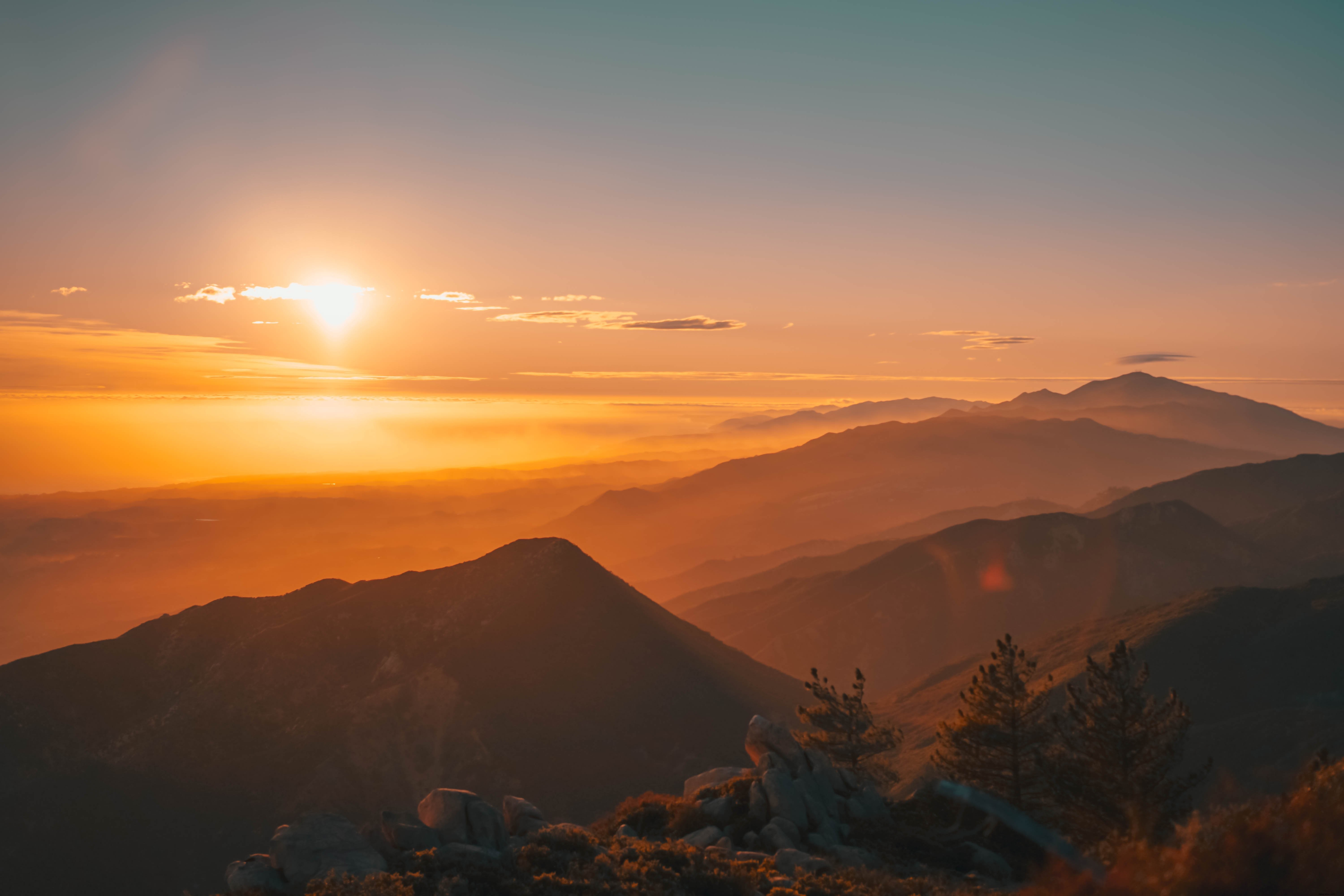 Foto do pôr do sol sobre montanhas de nevoeiro