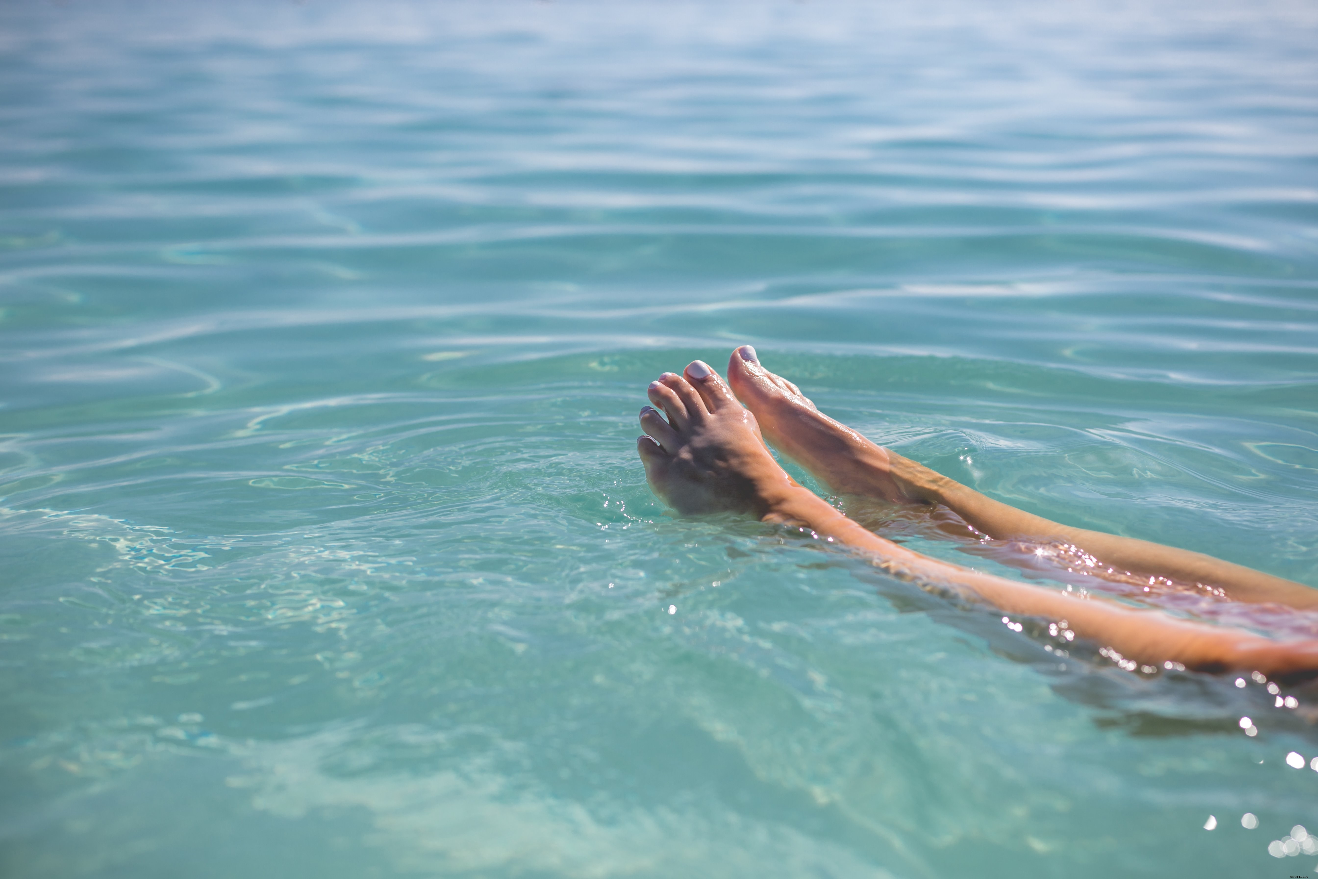 Piedi che galleggiano nell acqua blu foto