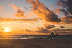 Uomo che rastrella la spiaggia al tramonto foto