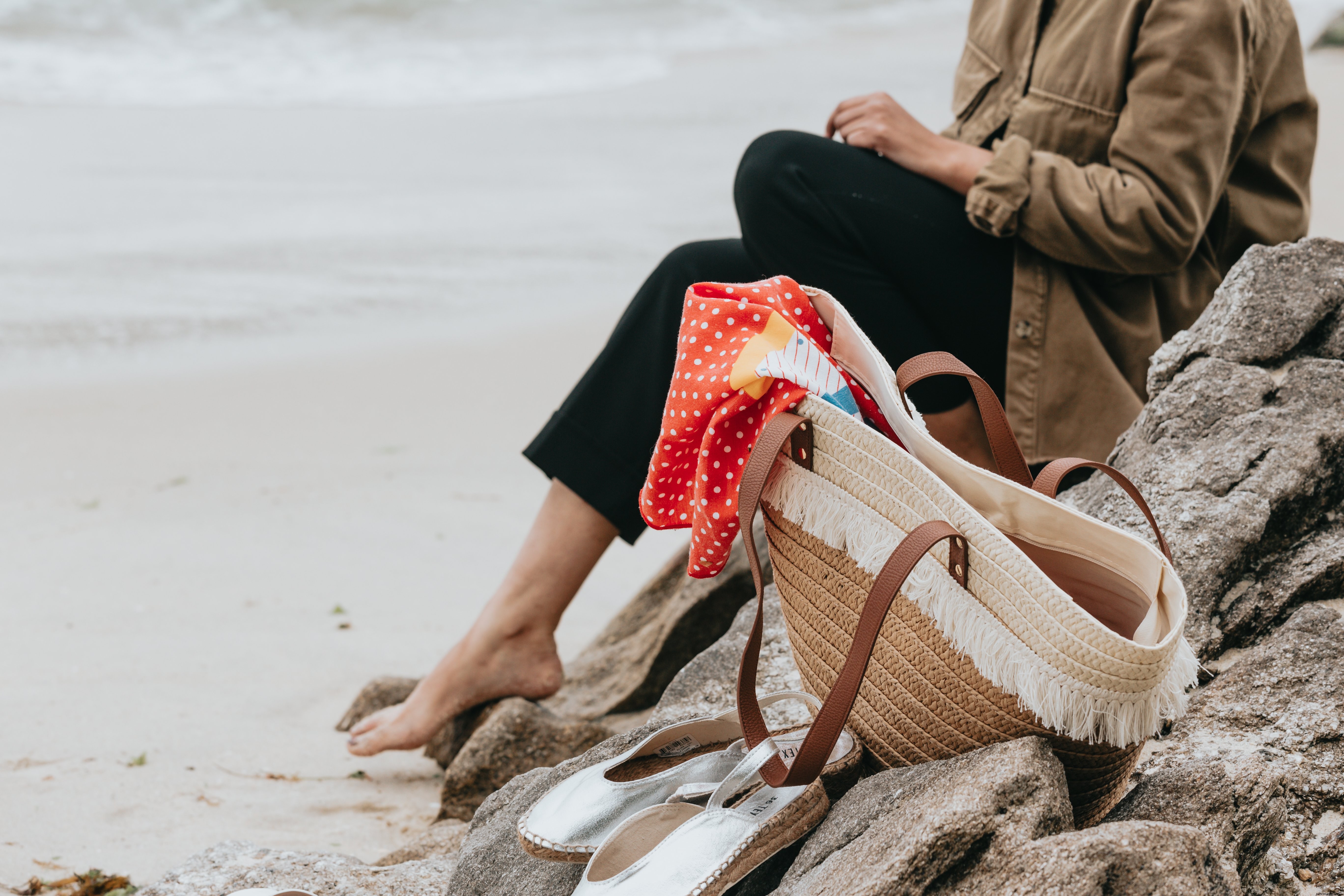 Sentado detrás de una bolsa de playa de mimbre en Rockys junto a la playa Foto