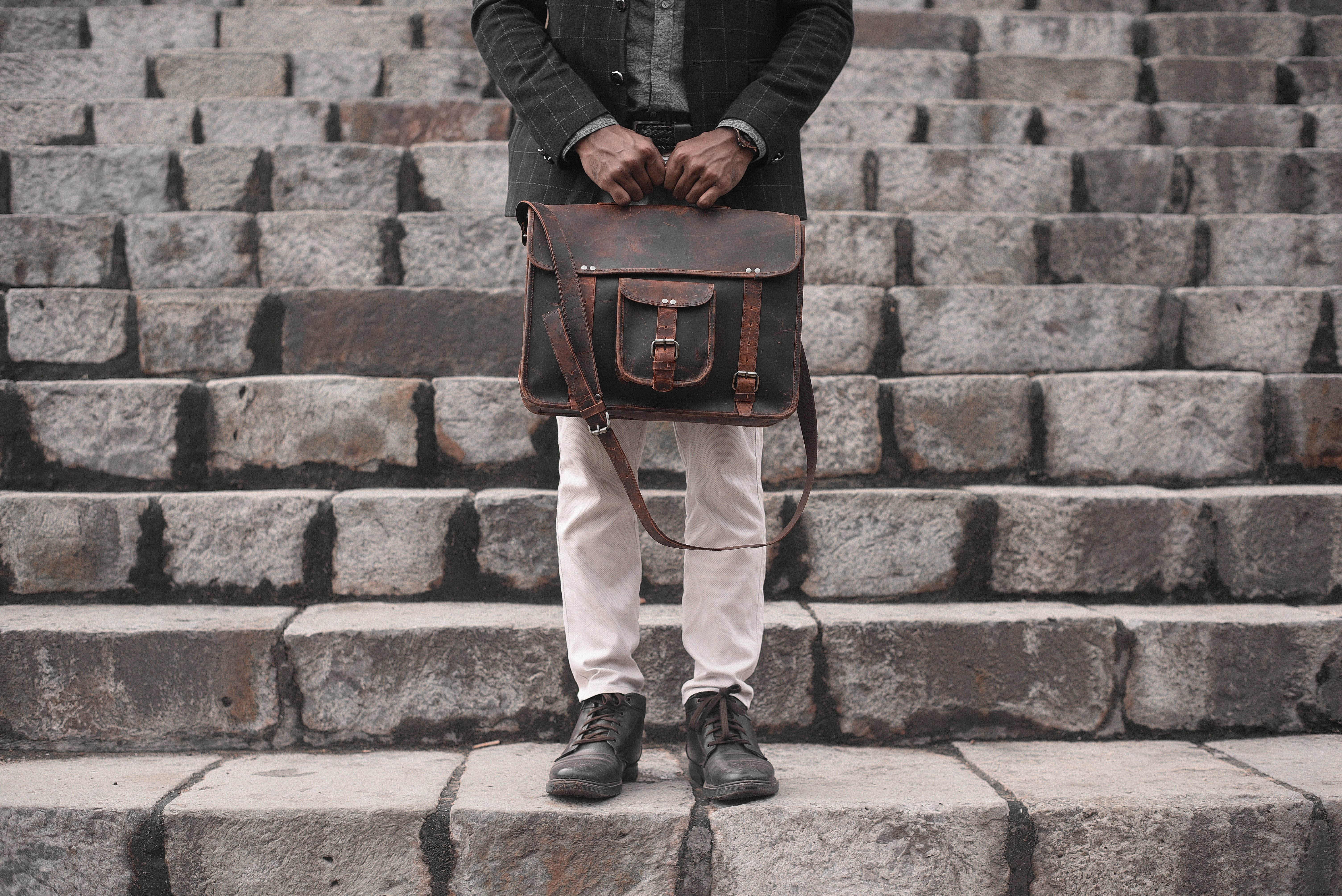 Hombre sujetando una bolsa de cuero en un conjunto de escaleras Foto