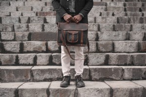 Foto de homem segurando uma bolsa de couro em uma escada