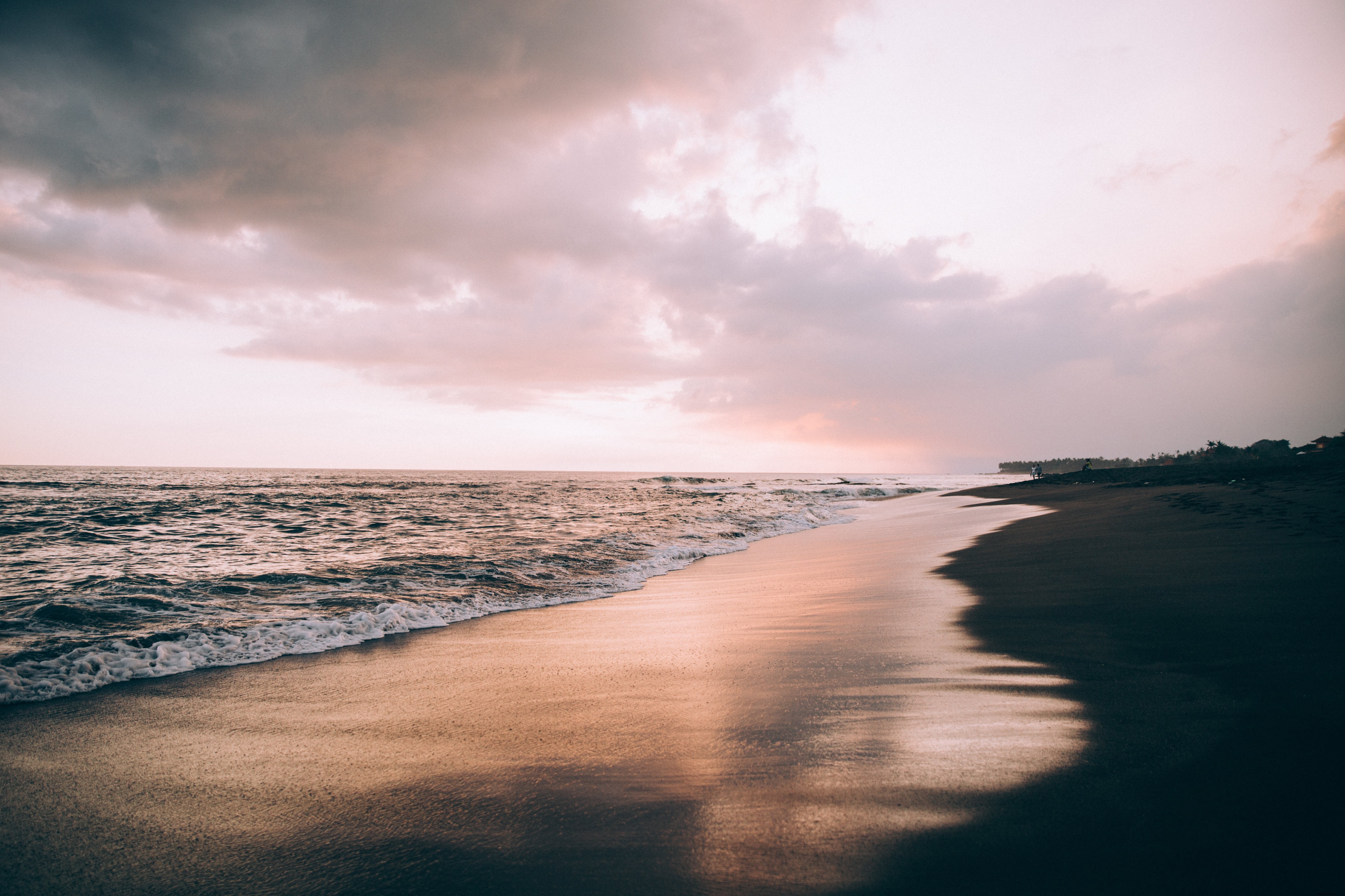 波に浸されたビーチの写真上のピンクの空の雲