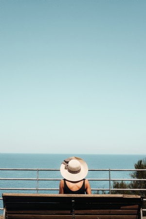 Pessoa sentada em um banco olhando para o oceano. Foto