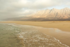 Montañas altas miran sobre el océano y la playa de arena Foto