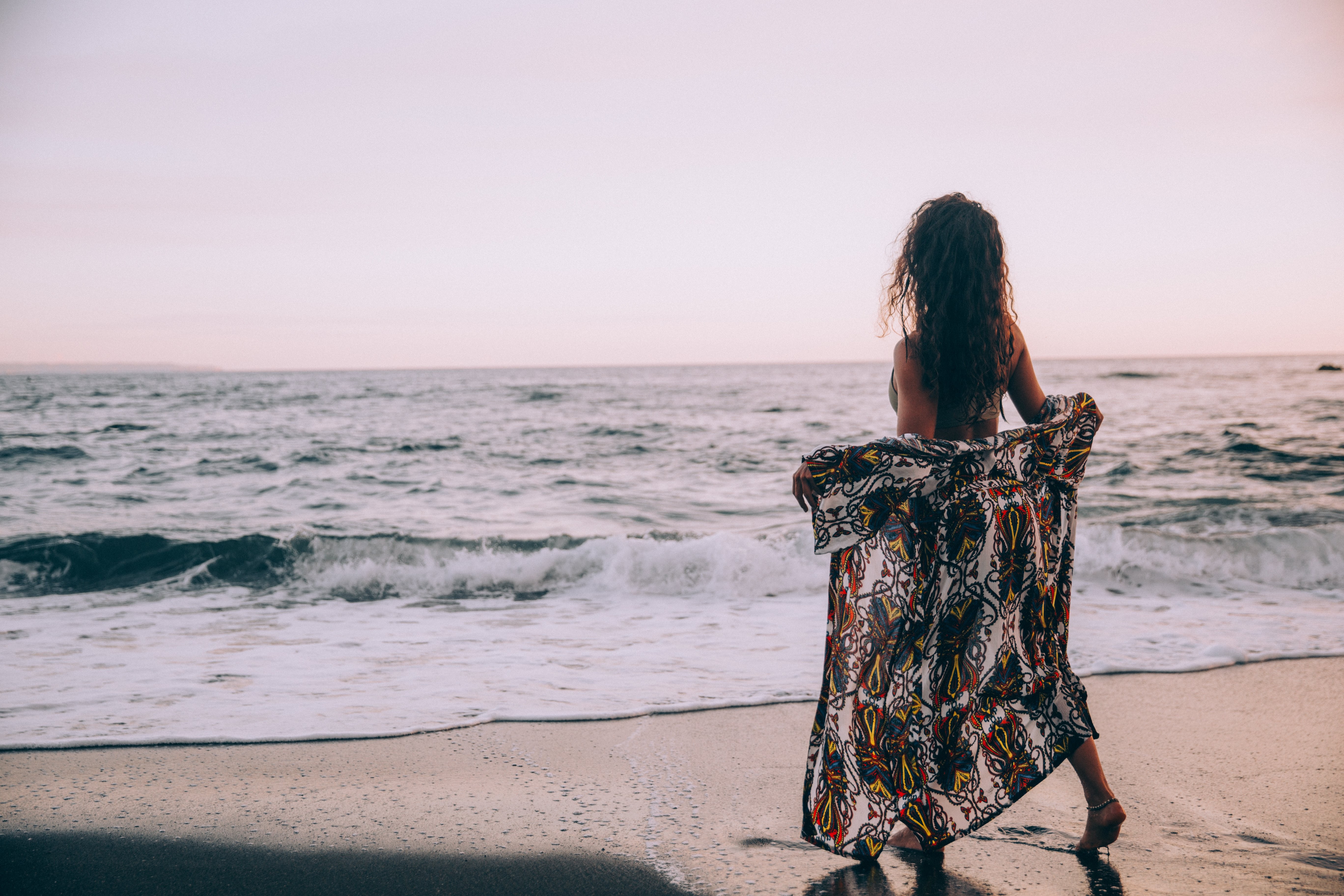 Uma mulher na praia abre seu sarongue na foto do Rolling Waves