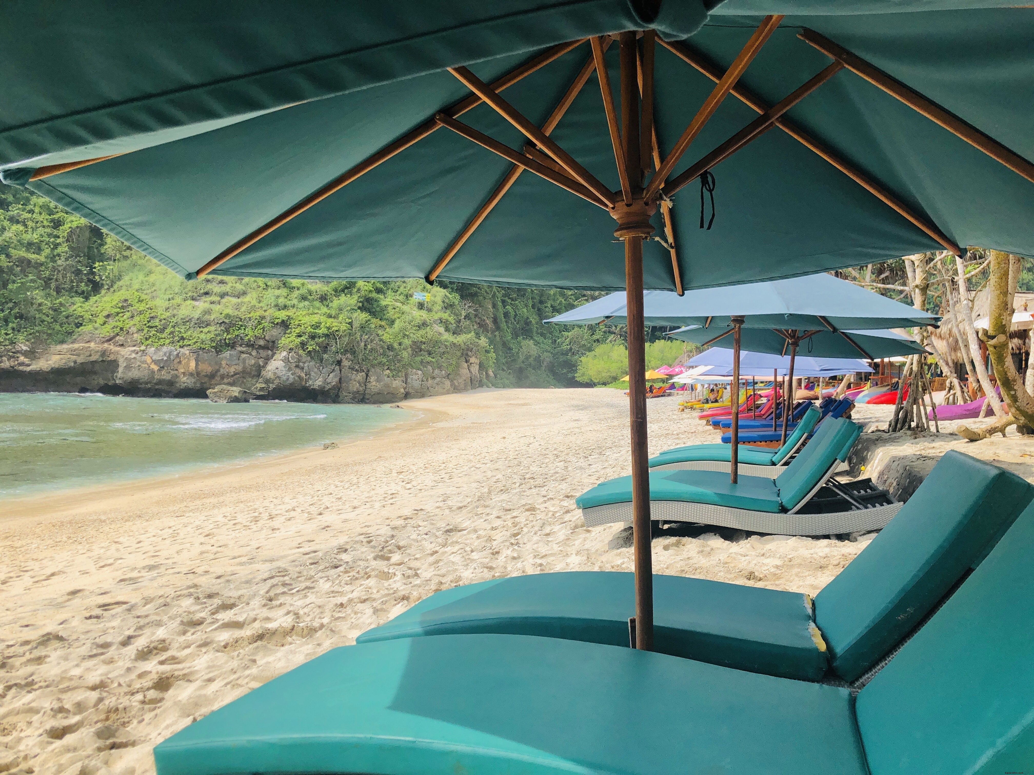 Cortinas e espreguiçadeiras azuis em uma foto de uma praia de areia dourada