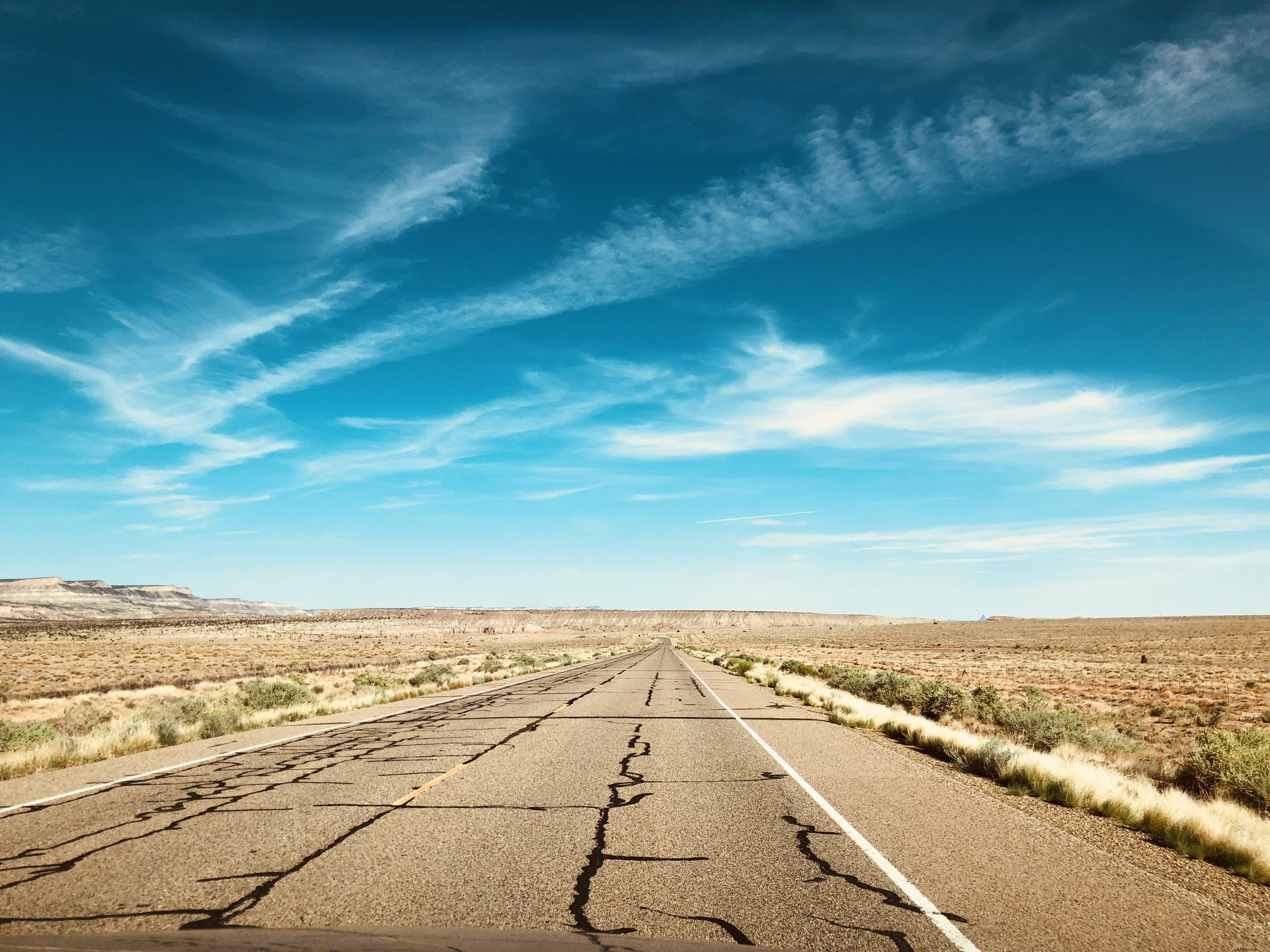 Foto de um céu azul brilhante sobre uma estrada quebrada no deserto