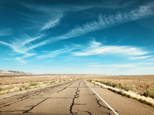 Foto de um céu azul brilhante sobre uma estrada quebrada no deserto