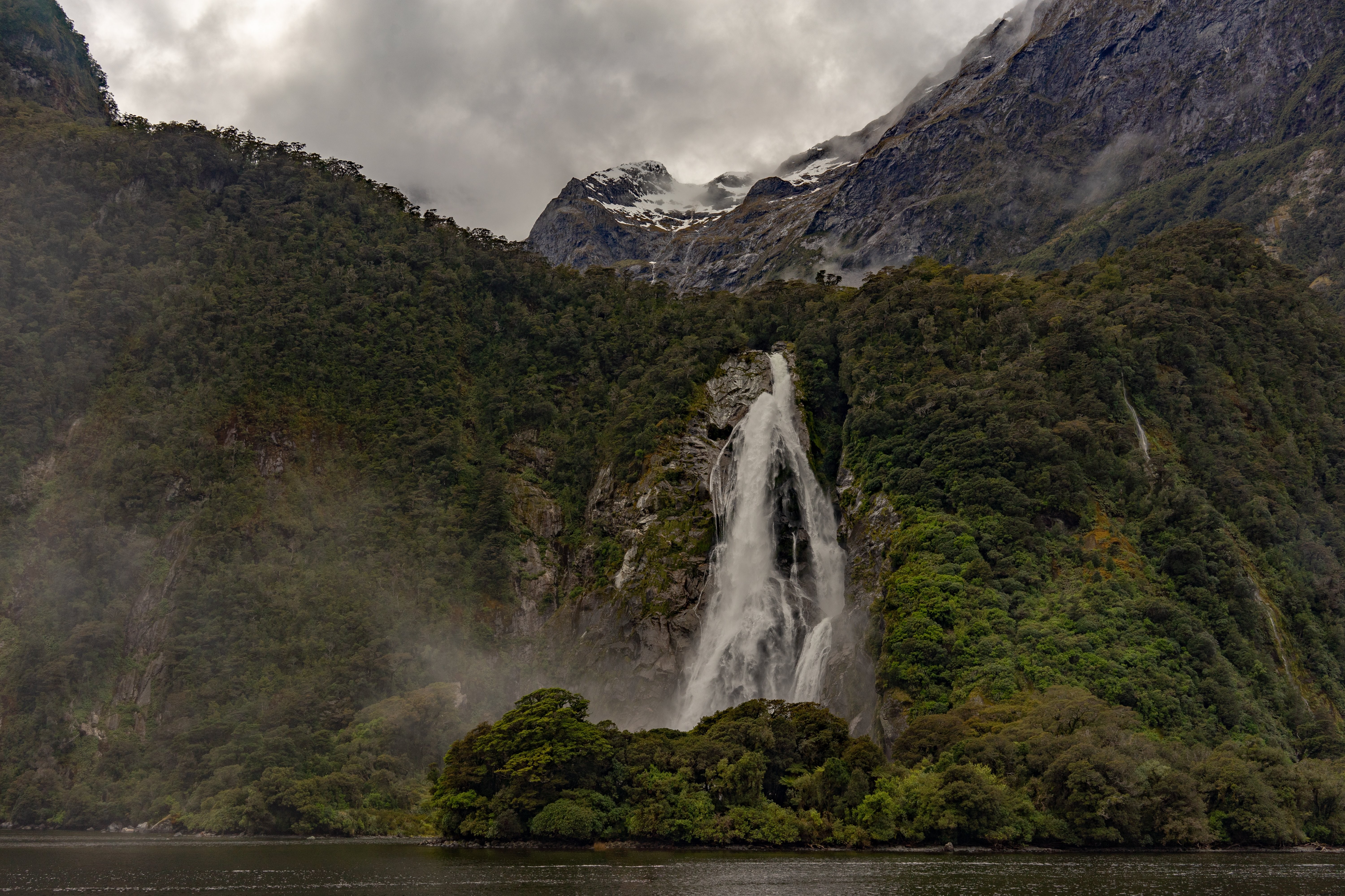 Cachoeira quebrando pedras abaixo de montanhas - foto