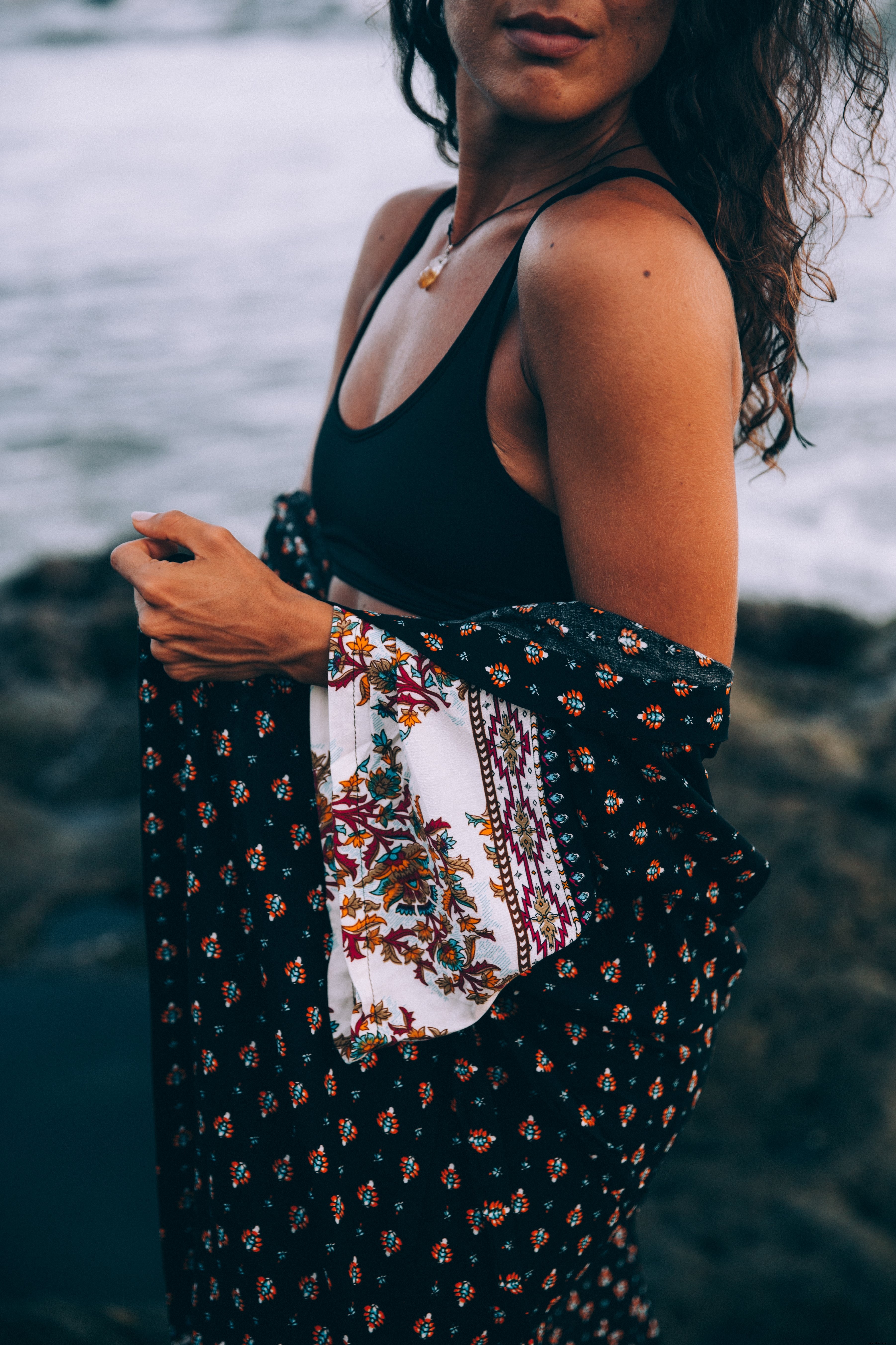 Une femme au bord de la mer avec un châle à motifs drapé dans les bras Photo