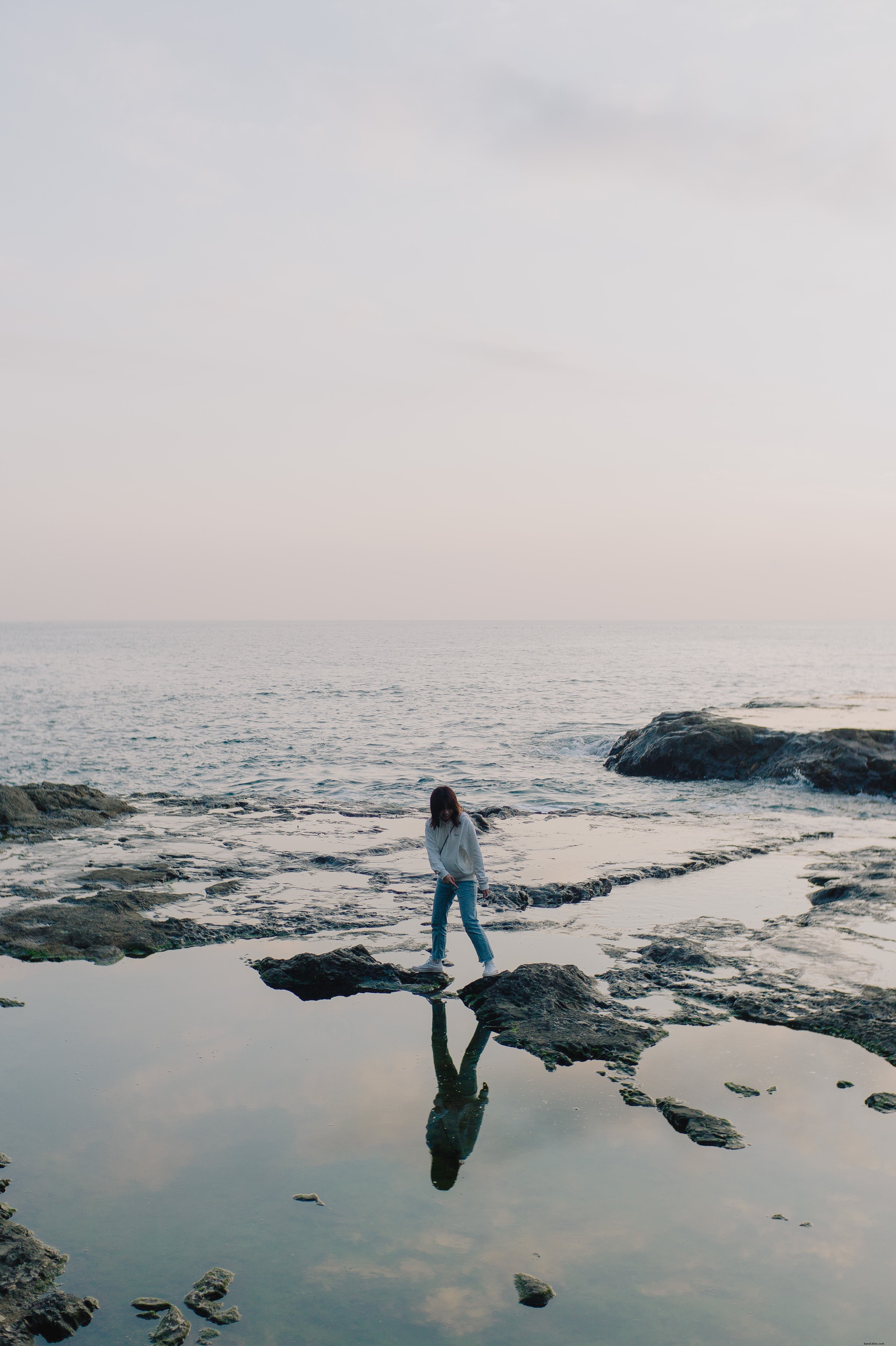 Personne se dresse sur des rochers poussant hors de l océan Photo du rivage