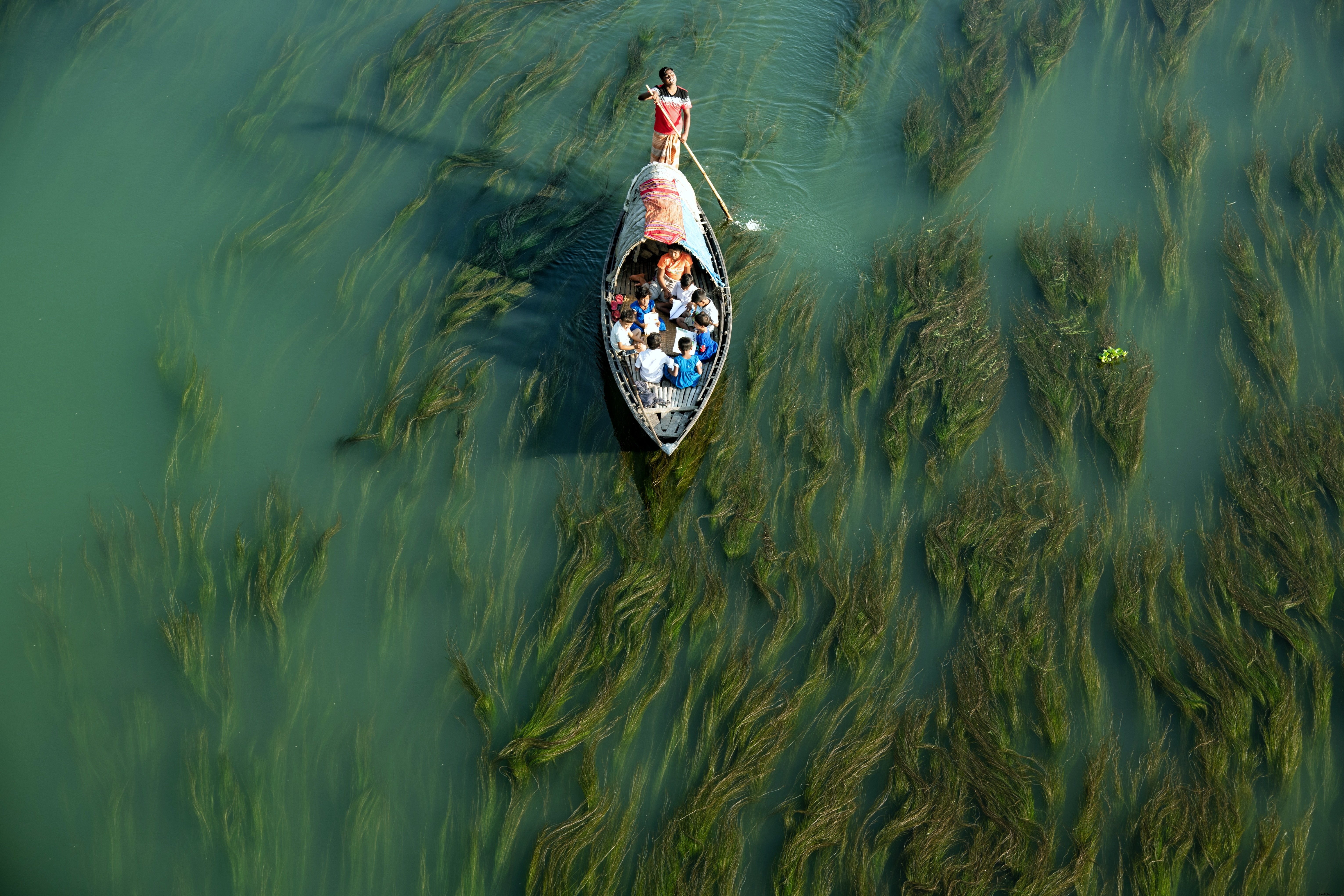 Un hombre empujando un bote pequeño a través de aguas poco profundas Foto