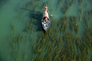 Un hombre empujando un bote pequeño a través de aguas poco profundas Foto