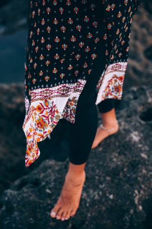 Um xale pendurado sobre os pés de uma mulher em leggings pretas Foto