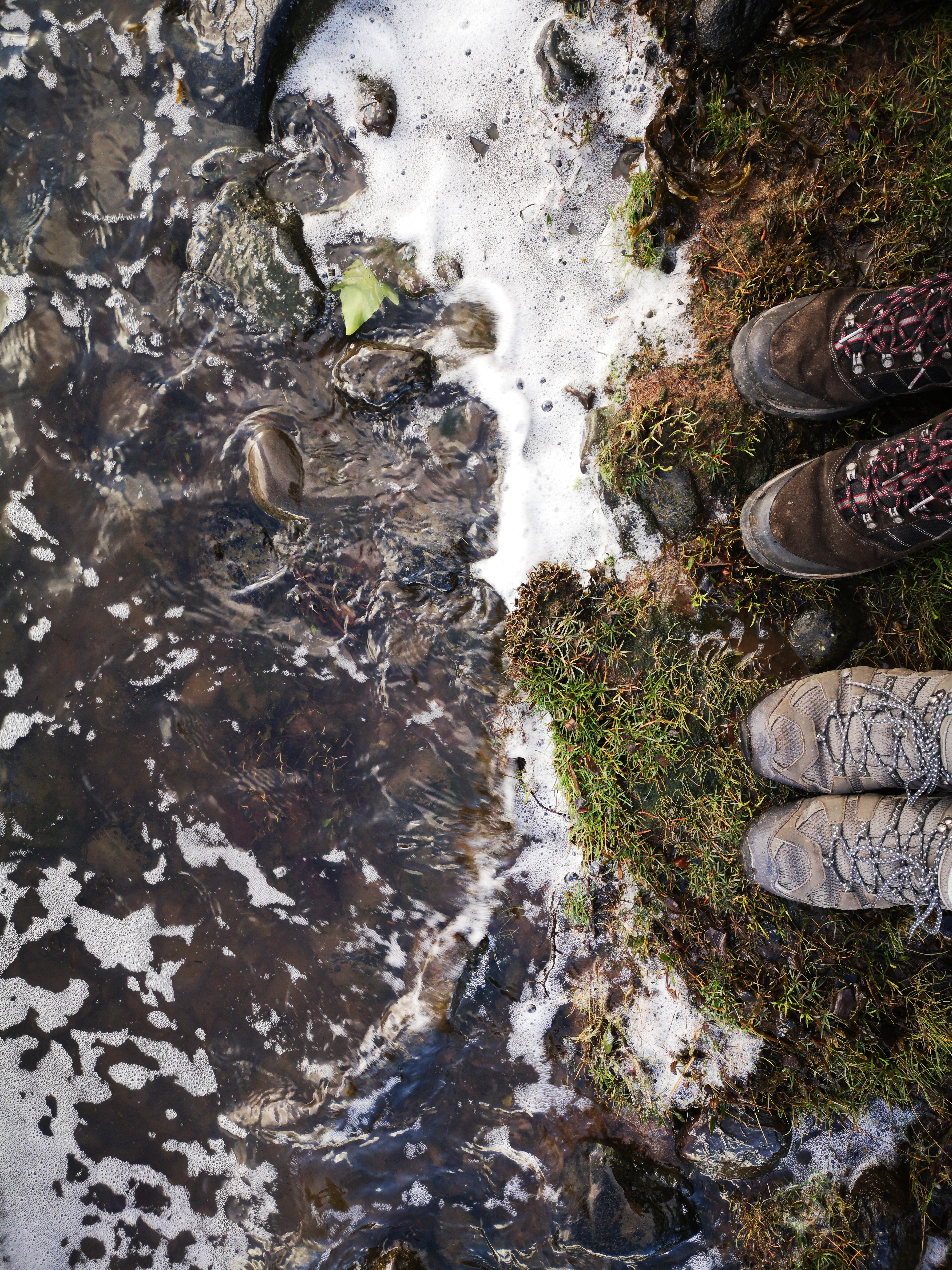 La rivière rencontre les rives où deux paires de bottes sont photo