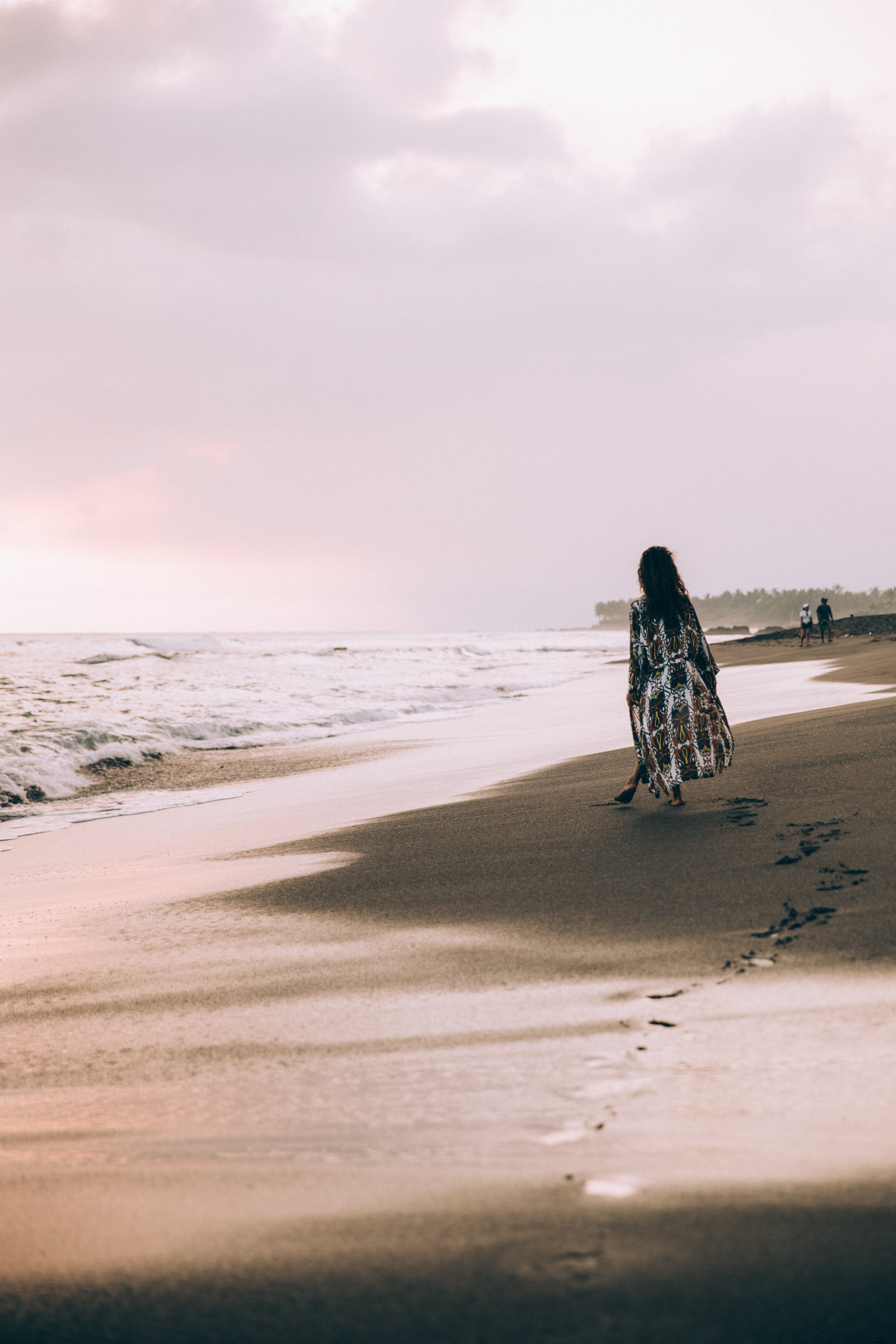 Una donna posa con la cavigliera sulla foto di una spiaggia rocciosa