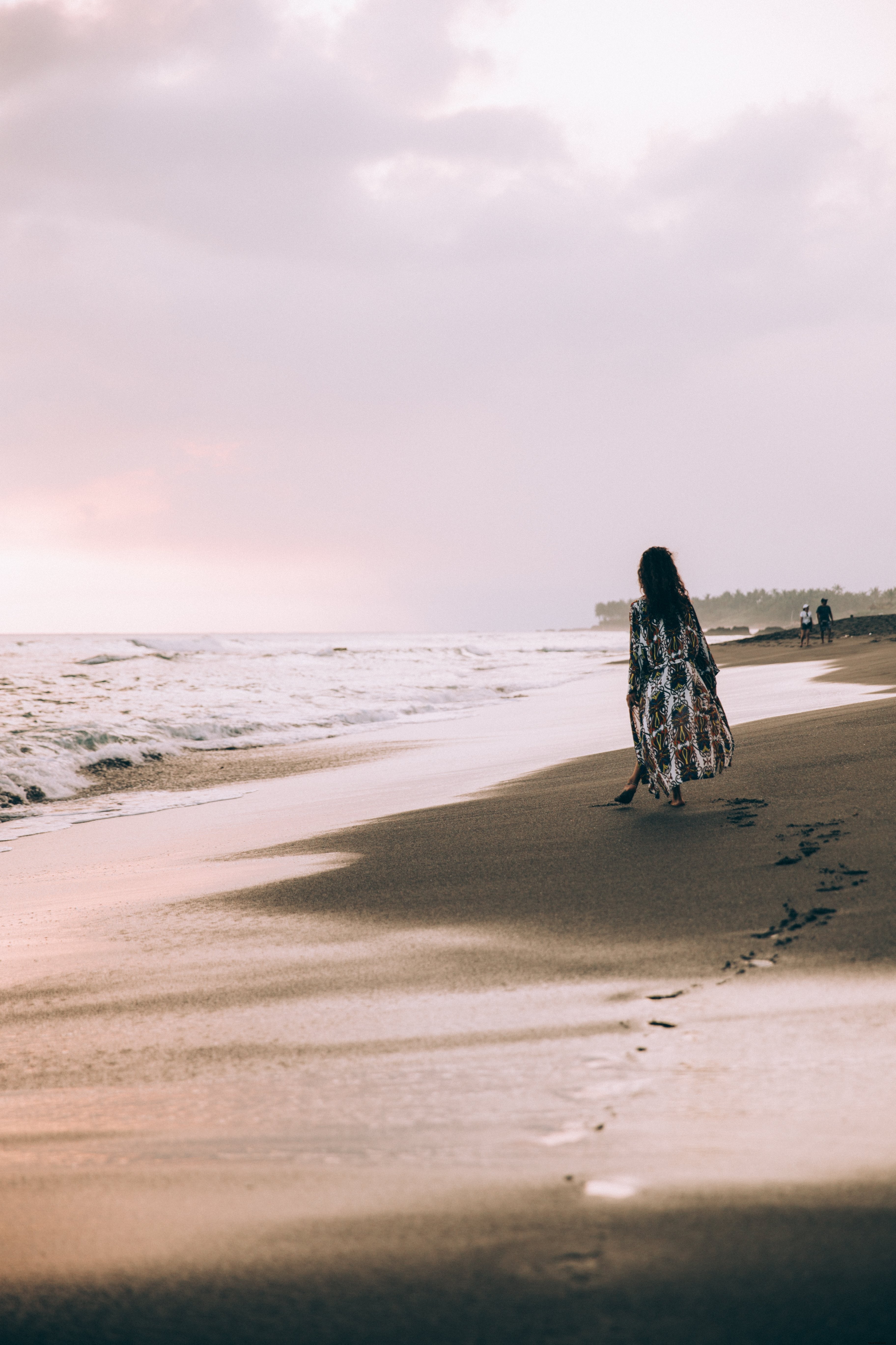 Foto de uma mulher posa com a tornozeleira na praia rochosa