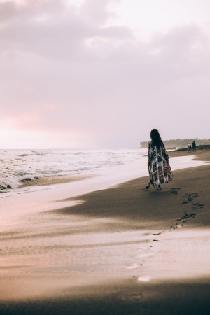 Foto de uma mulher posa com a tornozeleira na praia rochosa