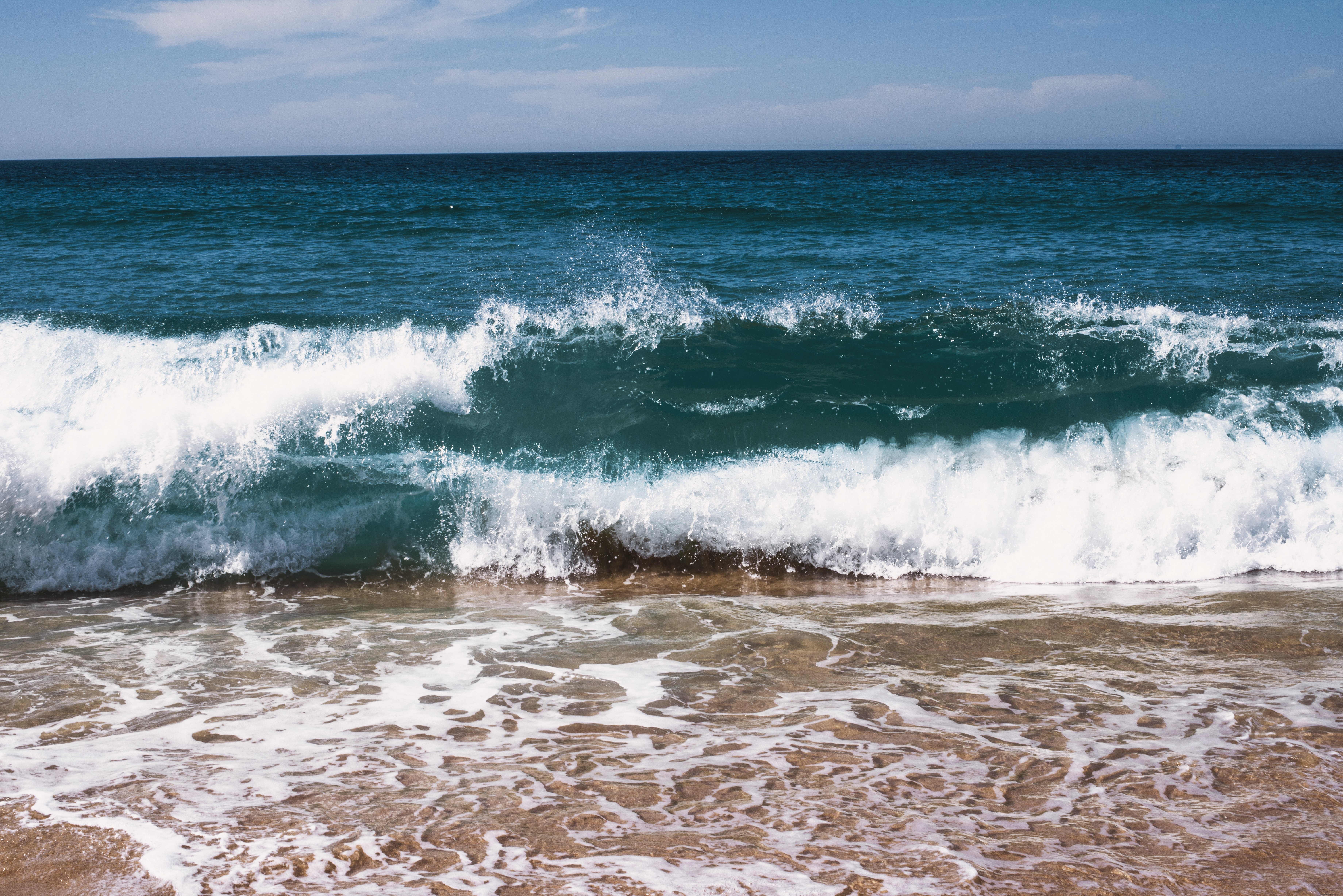 紺碧の水が海岸に流れ込む写真