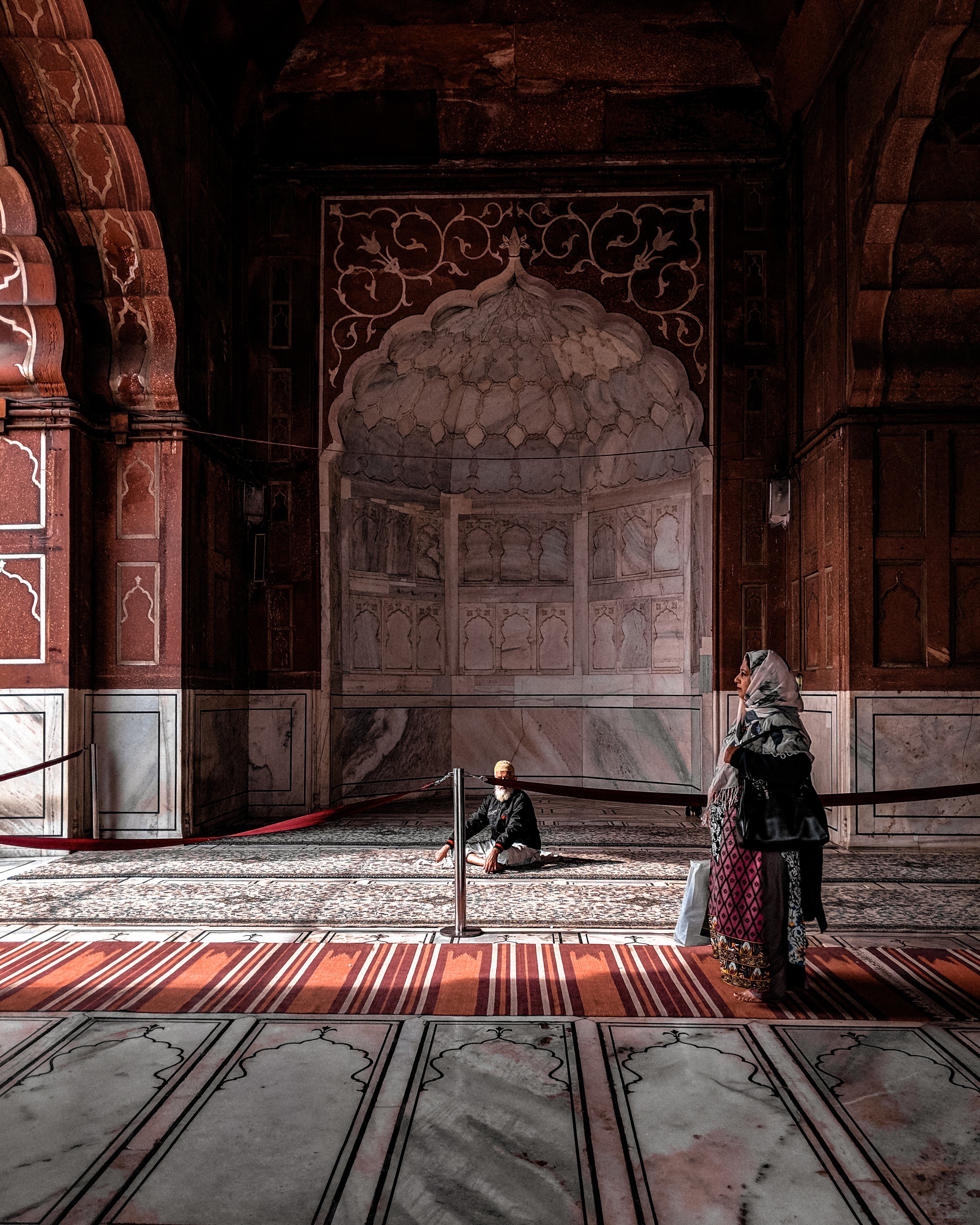 Une femme en rouge se promène dans une salle voûtée Photo