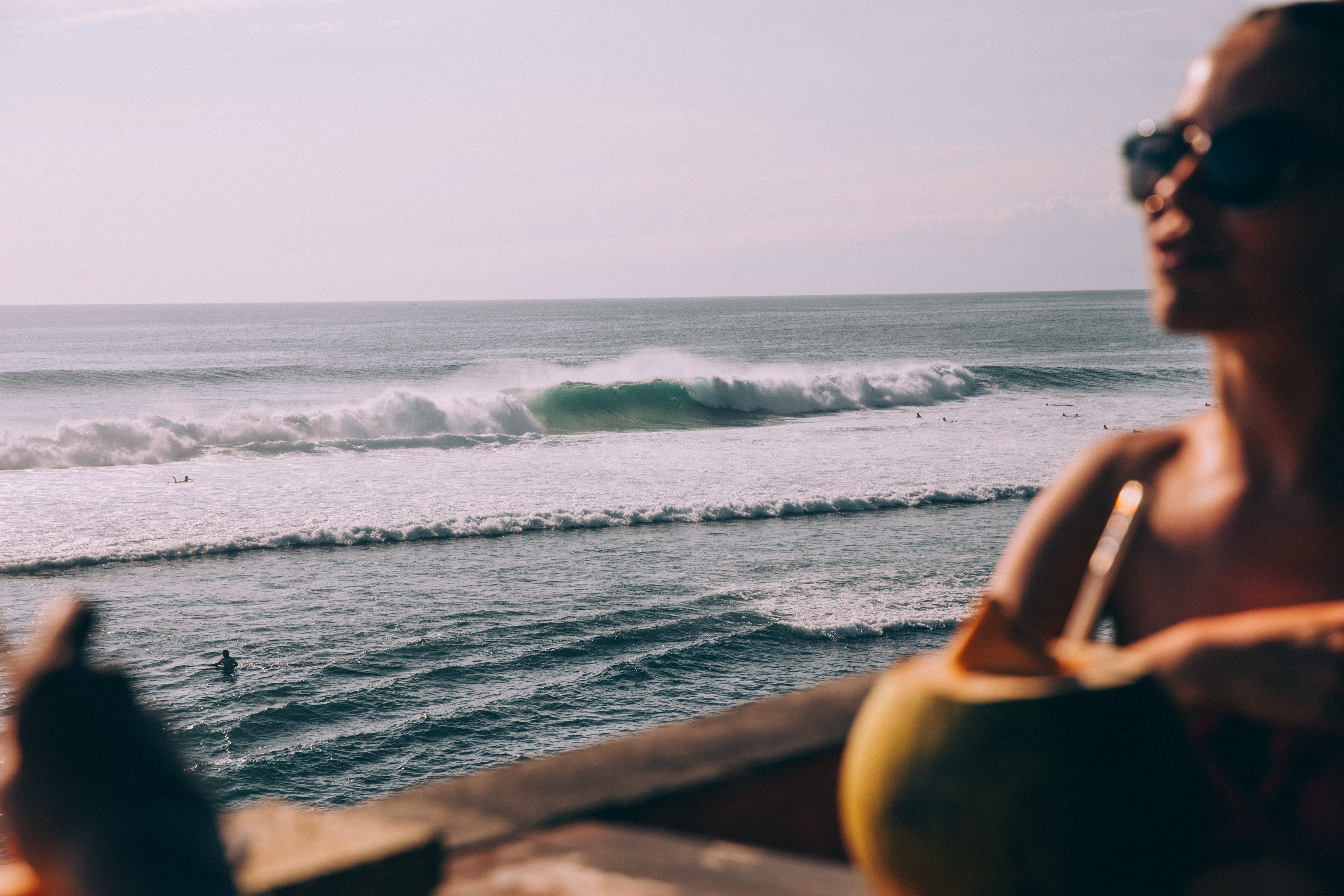 女性の写真のシルエットの背後にある距離で砕ける海の波