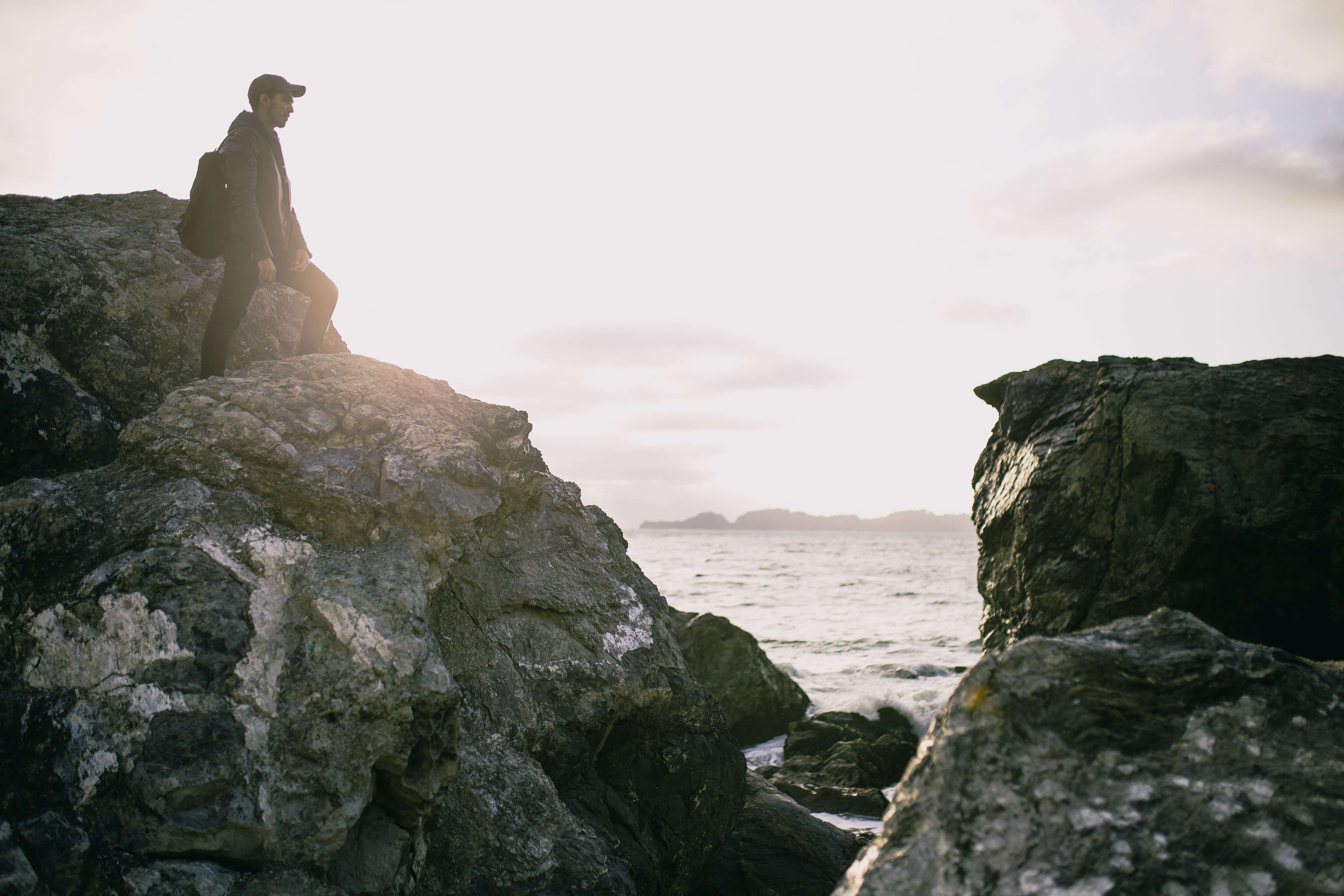 Caminante se encuentra en una roca alta junto a la foto del océano