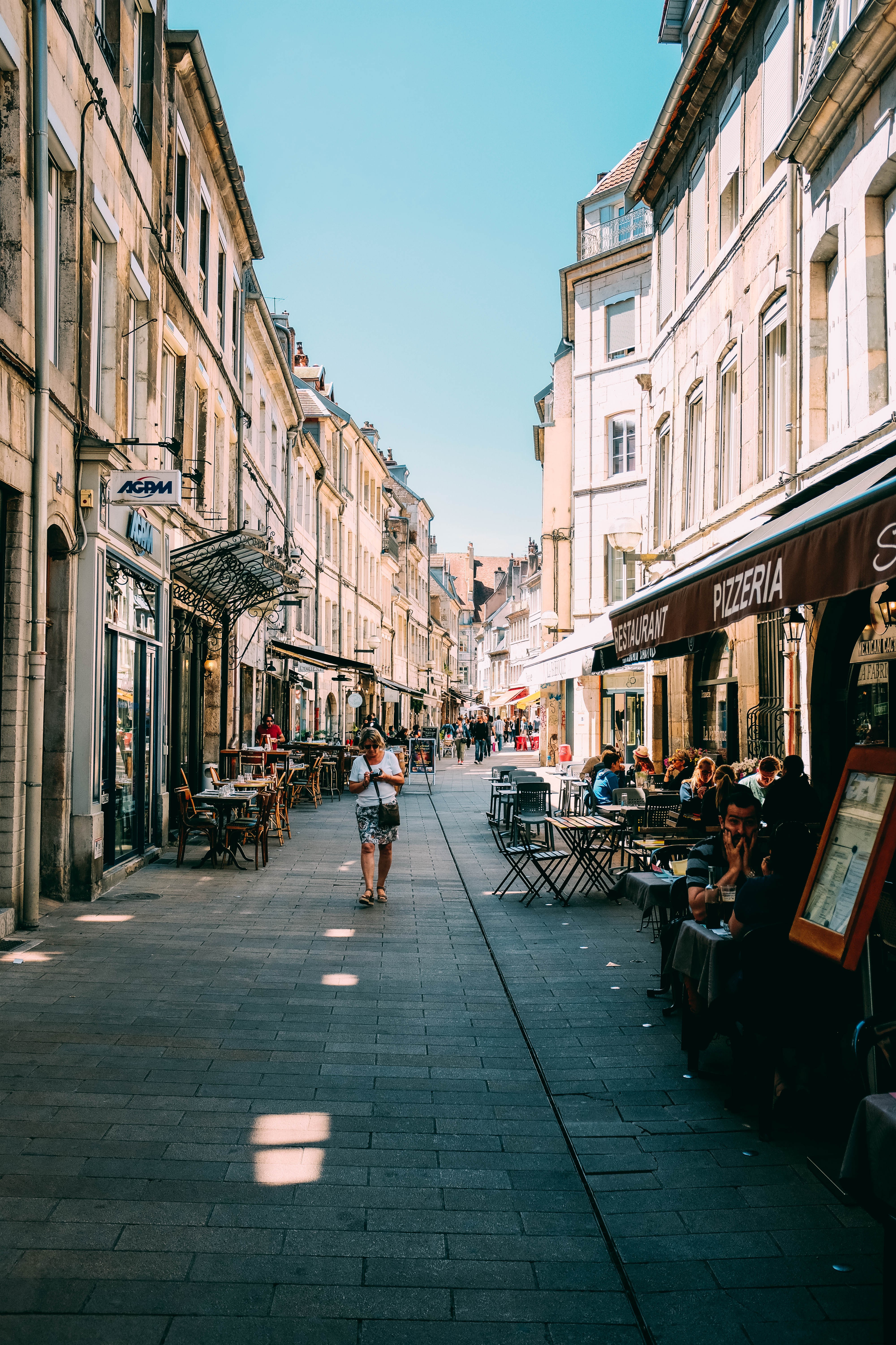 Turistas sentam do lado de fora de uma pizzaria em uma foto de rua europeia