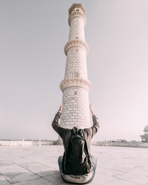 Um homem enquadra a base de uma torre com os braços. Foto