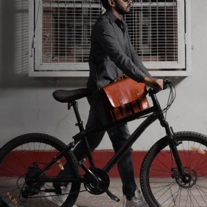 Homem andando de bicicleta com foto de bolsa mensageiro de couro