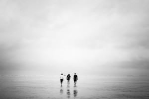 3人の男性が干潮のビーチの写真の上を歩きます