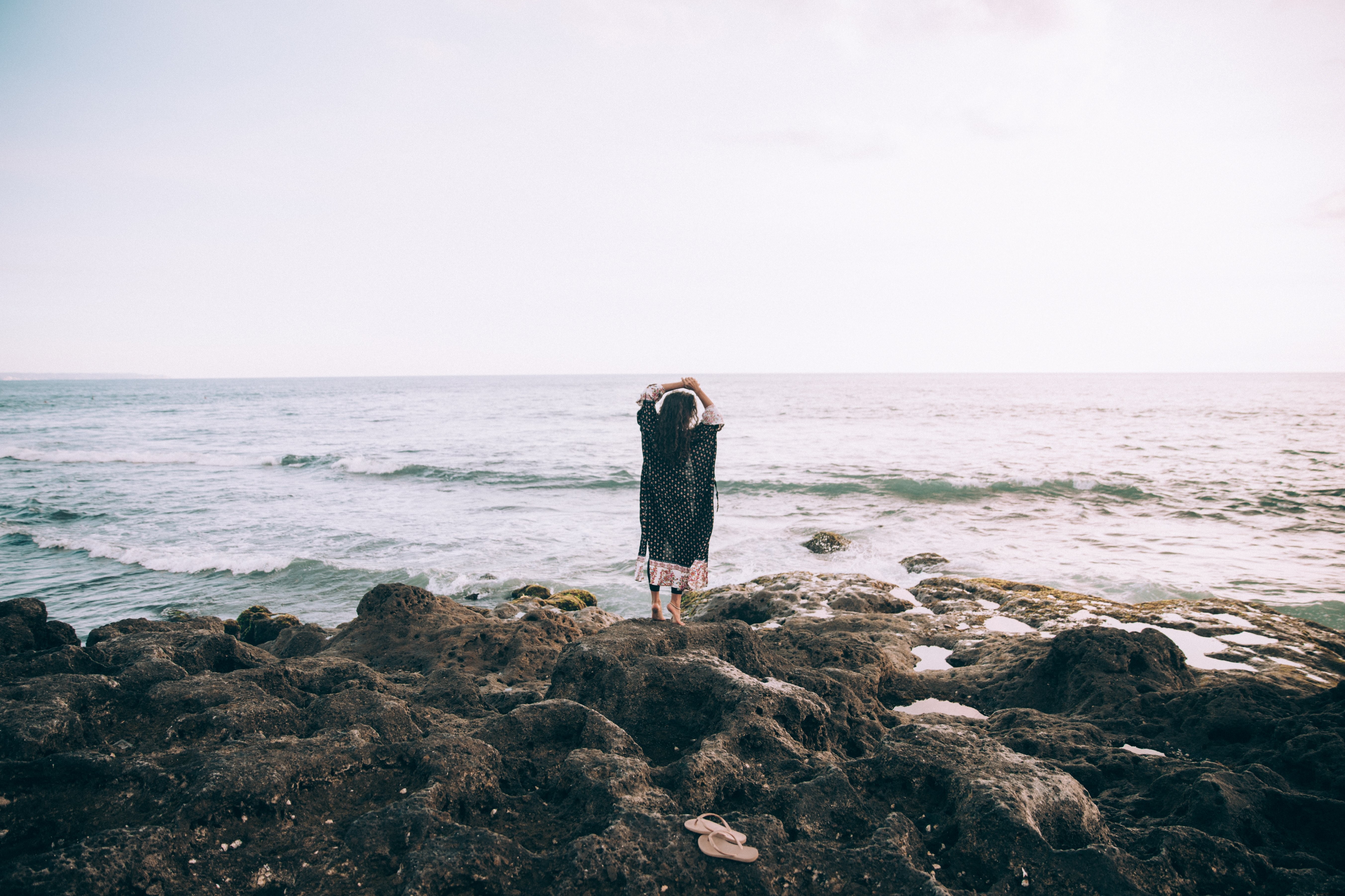 Seorang Wanita Di Tepi Pantai Mengangkat Tangannya Dalam Foto Lamunan