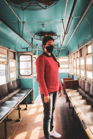 Foto de pessoa com máscara facial preta em um ônibus azul
