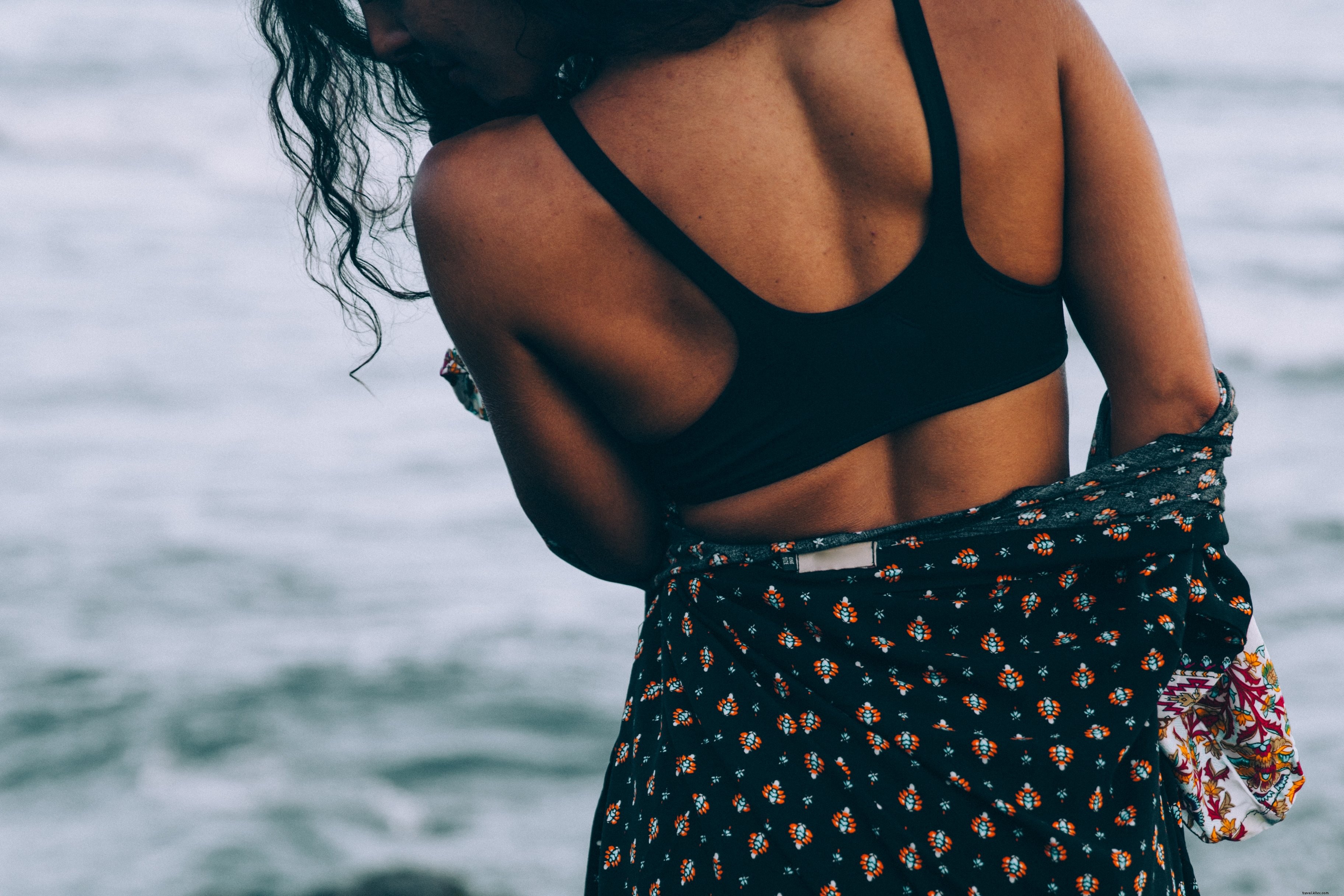 Una mujer bronceada en una bata de playa se encuentra junto al mar Foto