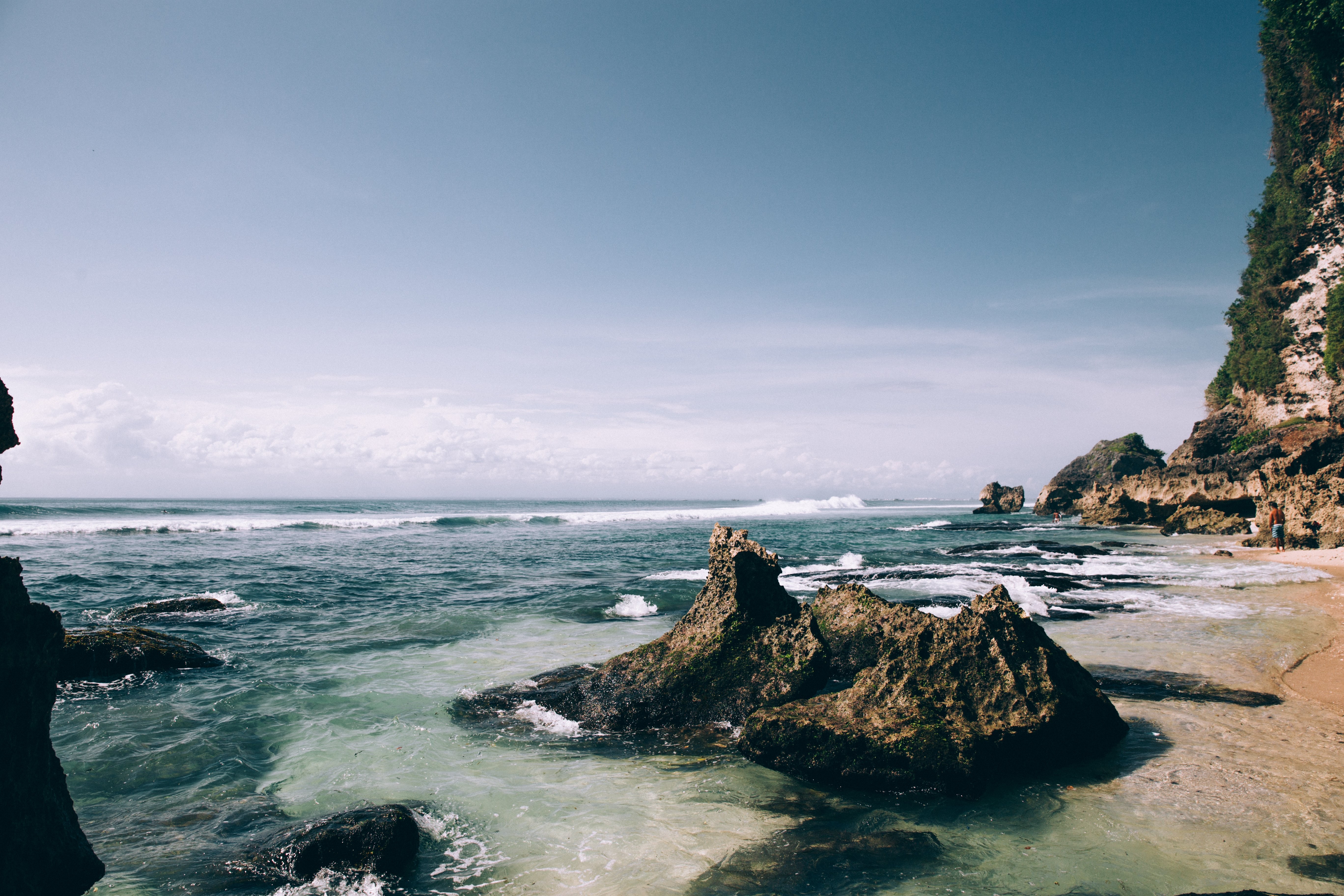 Foto de playa de arena blanca salpicada de grandes cantos rodados