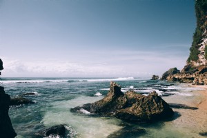 Praia de areia branca espalhada por grandes rochas
