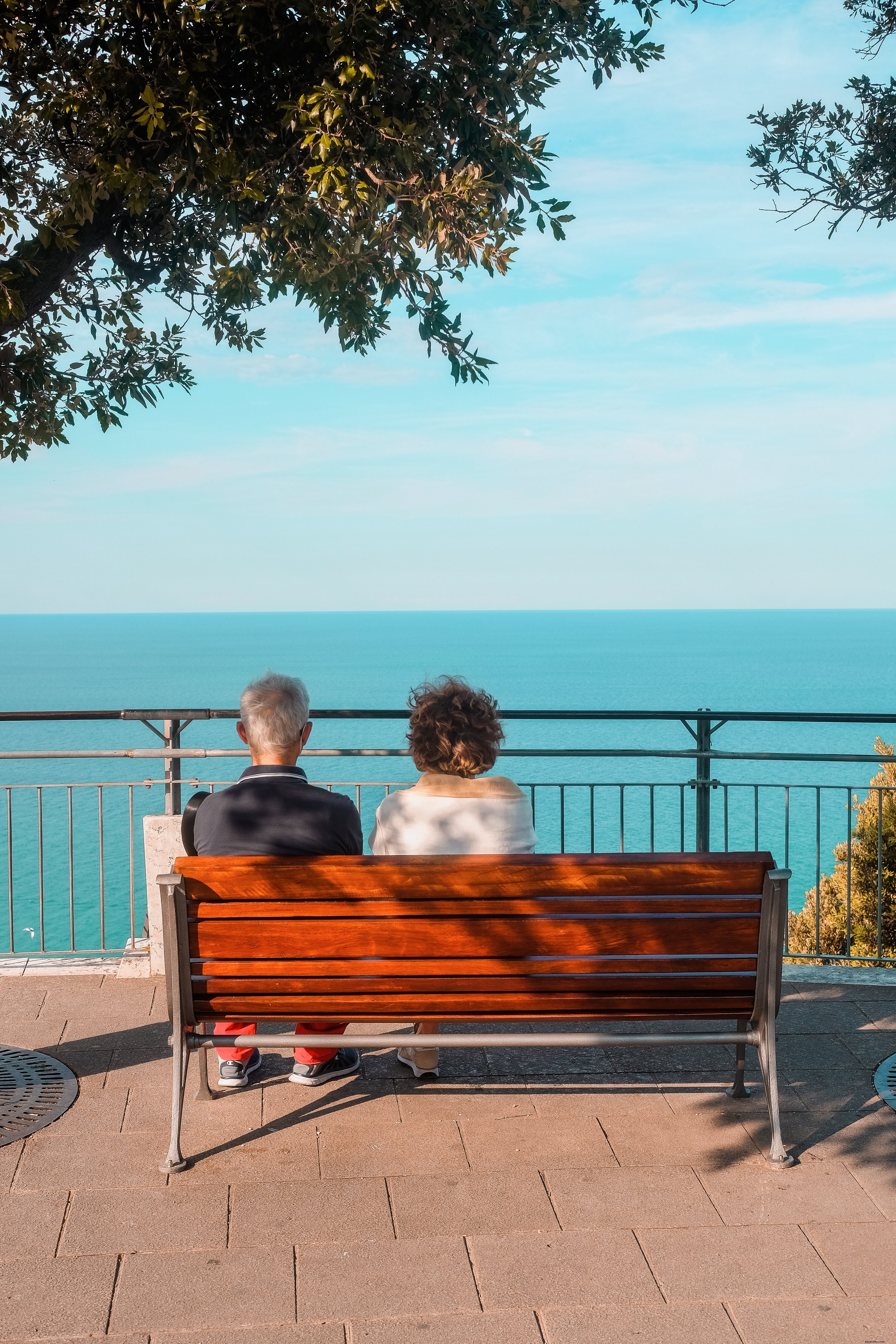 Le persone si siedono sulla panchina rossa e ammirano la foto del panorama