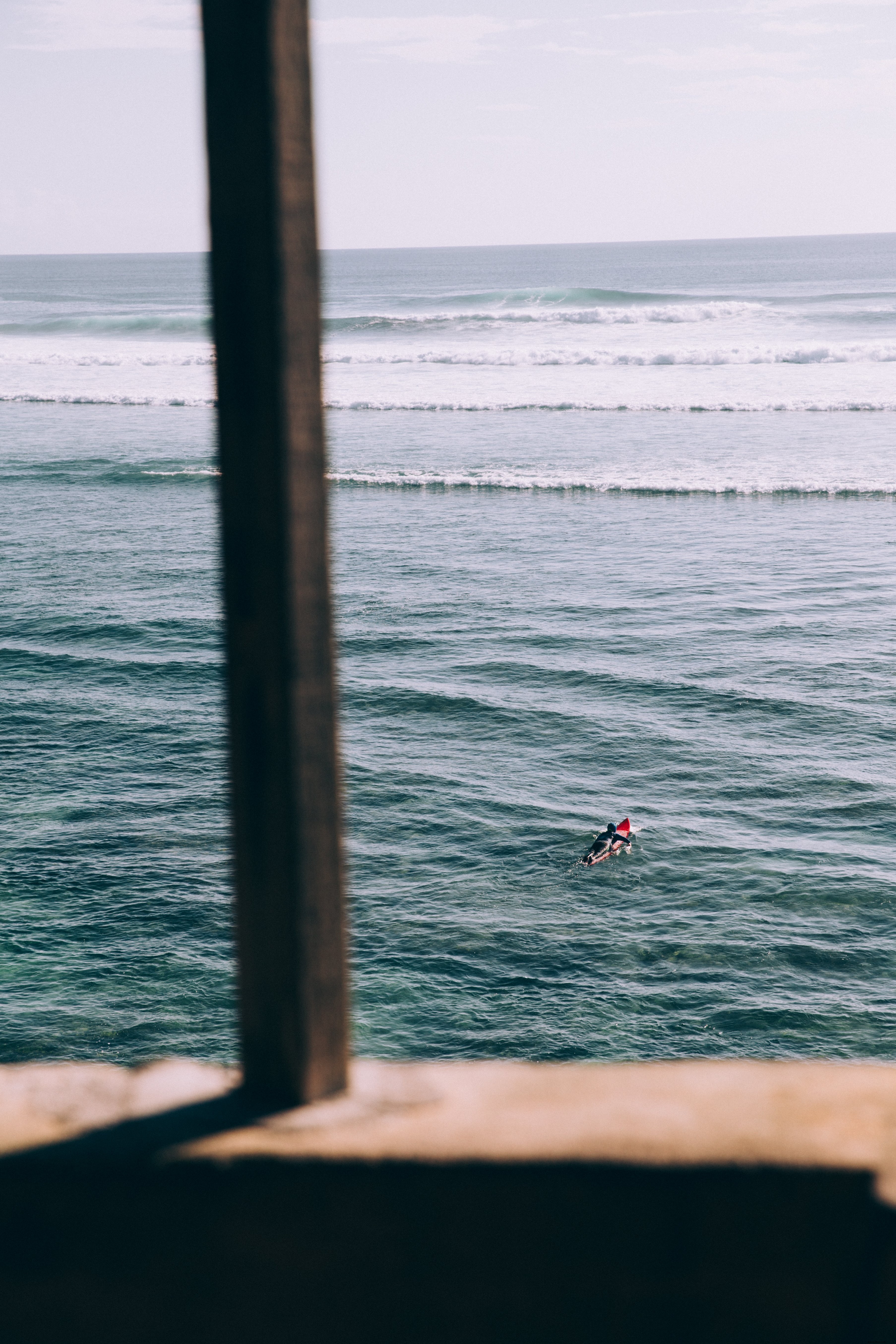 孤独なサーファーが波の写真にパドルアウト