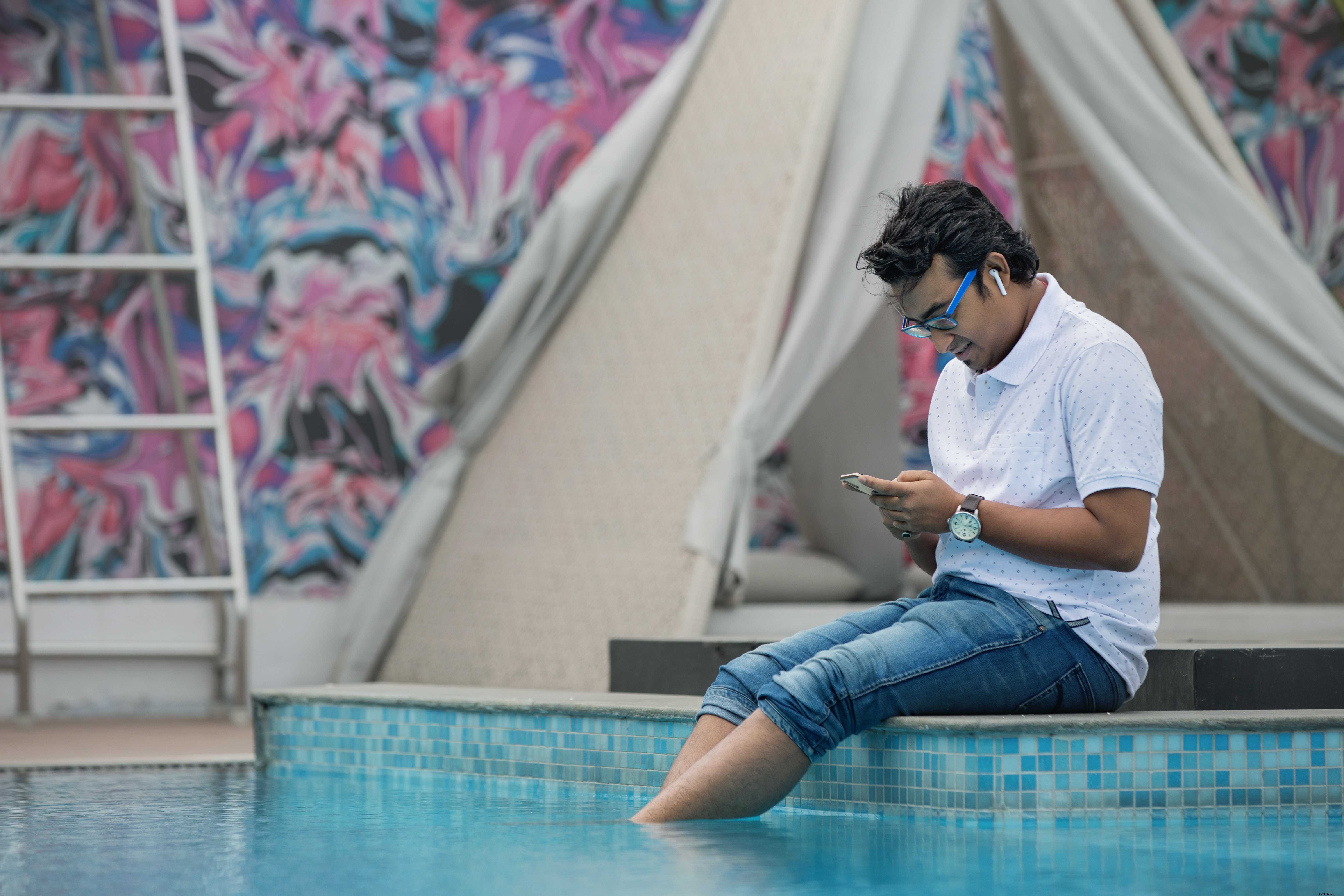 Foto de homem sentado à beira da piscina