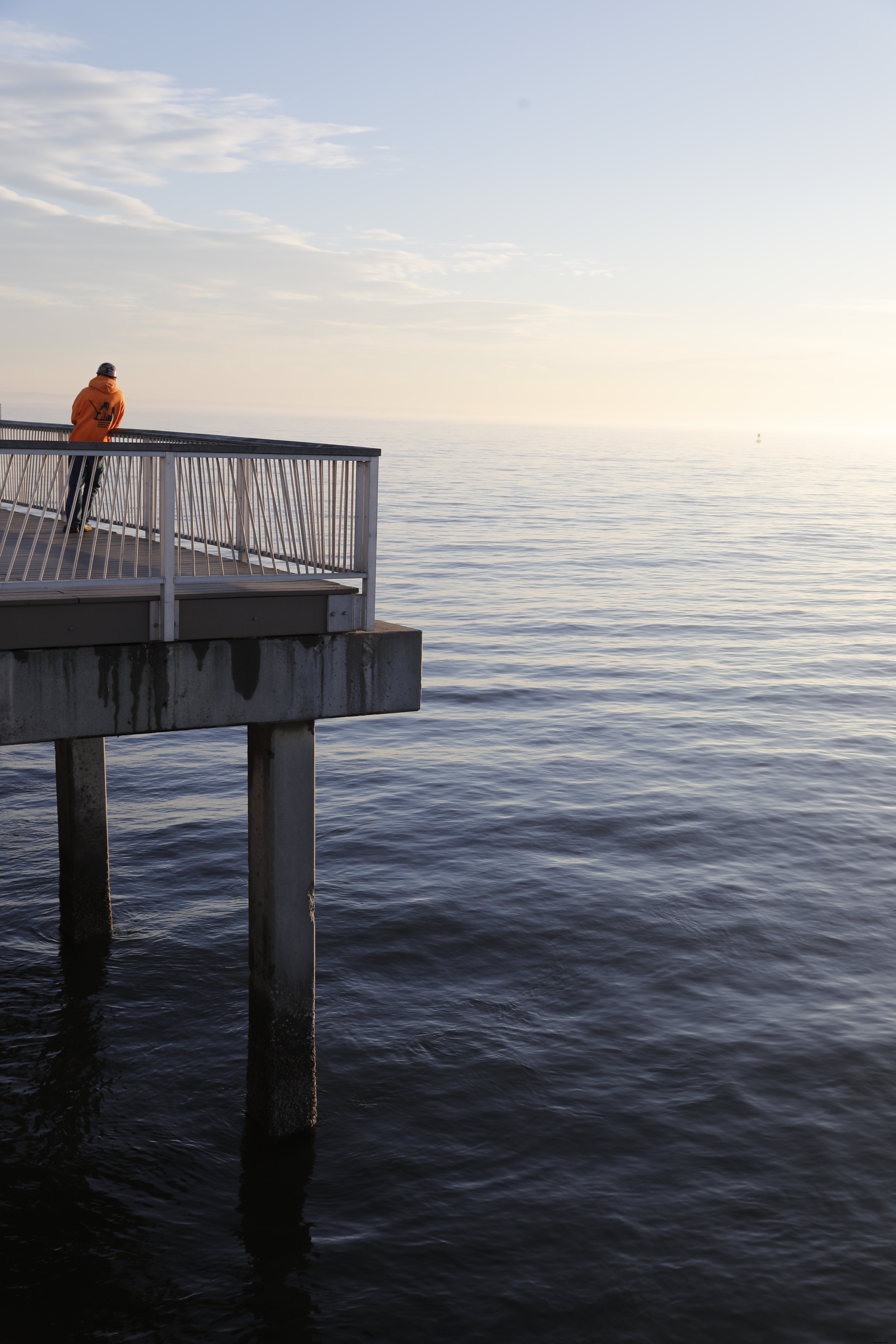 Hombre solitario se para en un muelle al atardecer Foto